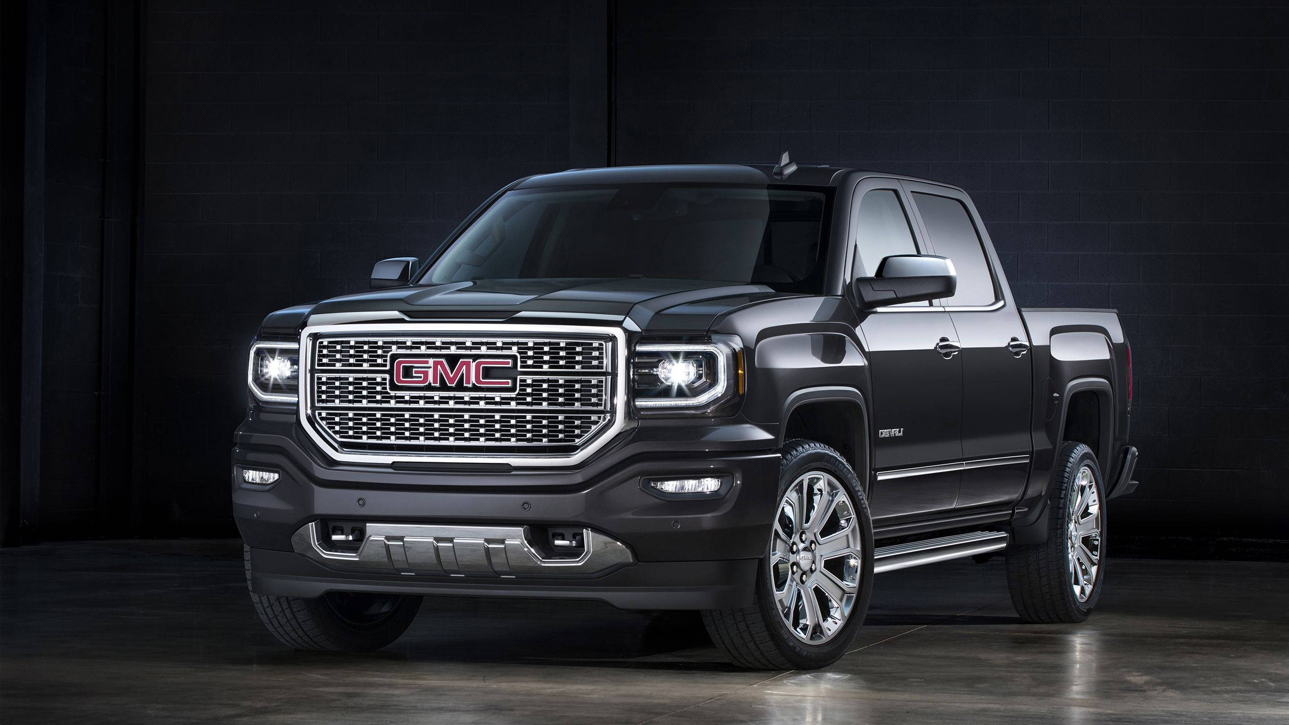Gmc 桌布 壁紙 — 一輛時尚的黑色GMC Sierra皮卡車，帶有鍍鉻裝飾和發光車頭燈，在黑暗的攝影棚環境中展示。