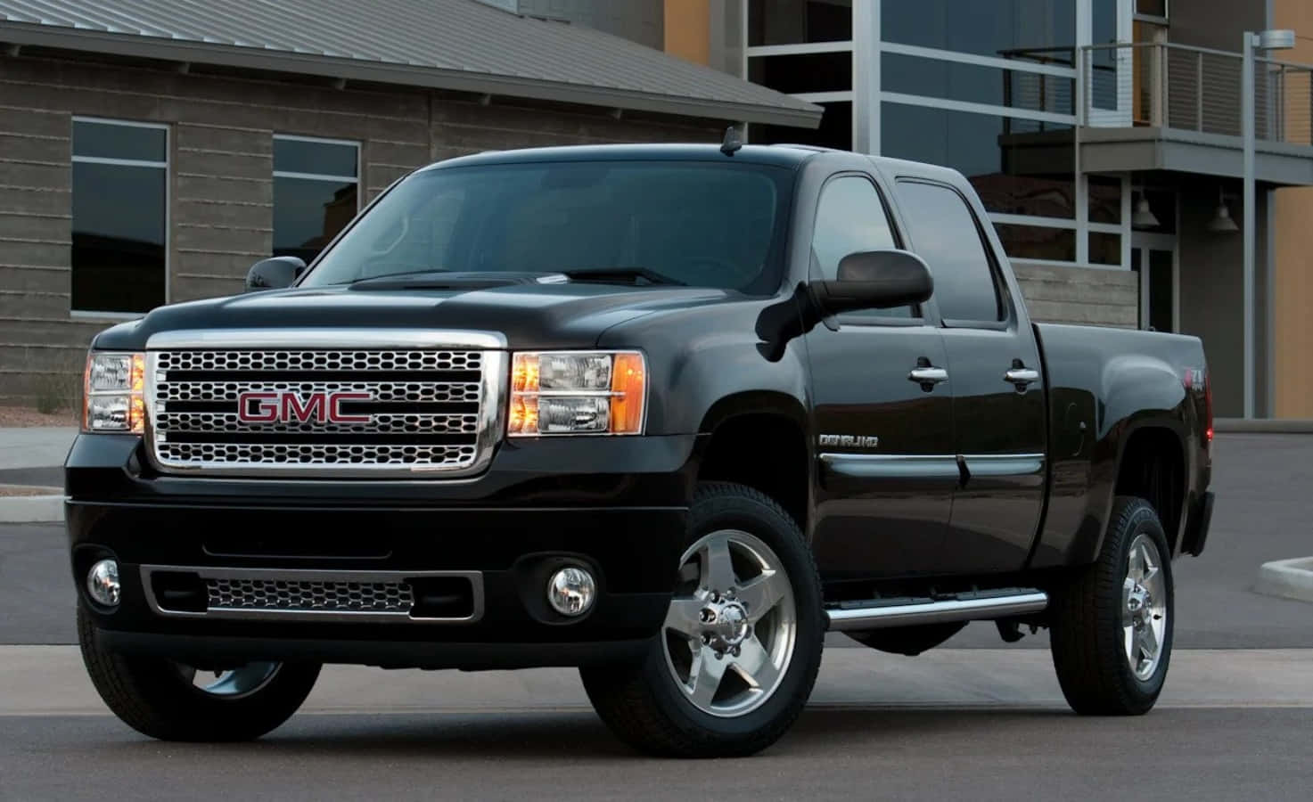 GMC 桌布 壁紙 — 一輛時尚的黑色GMC Sierra皮卡車停在現代建築前，建築物帶有反光窗戶。