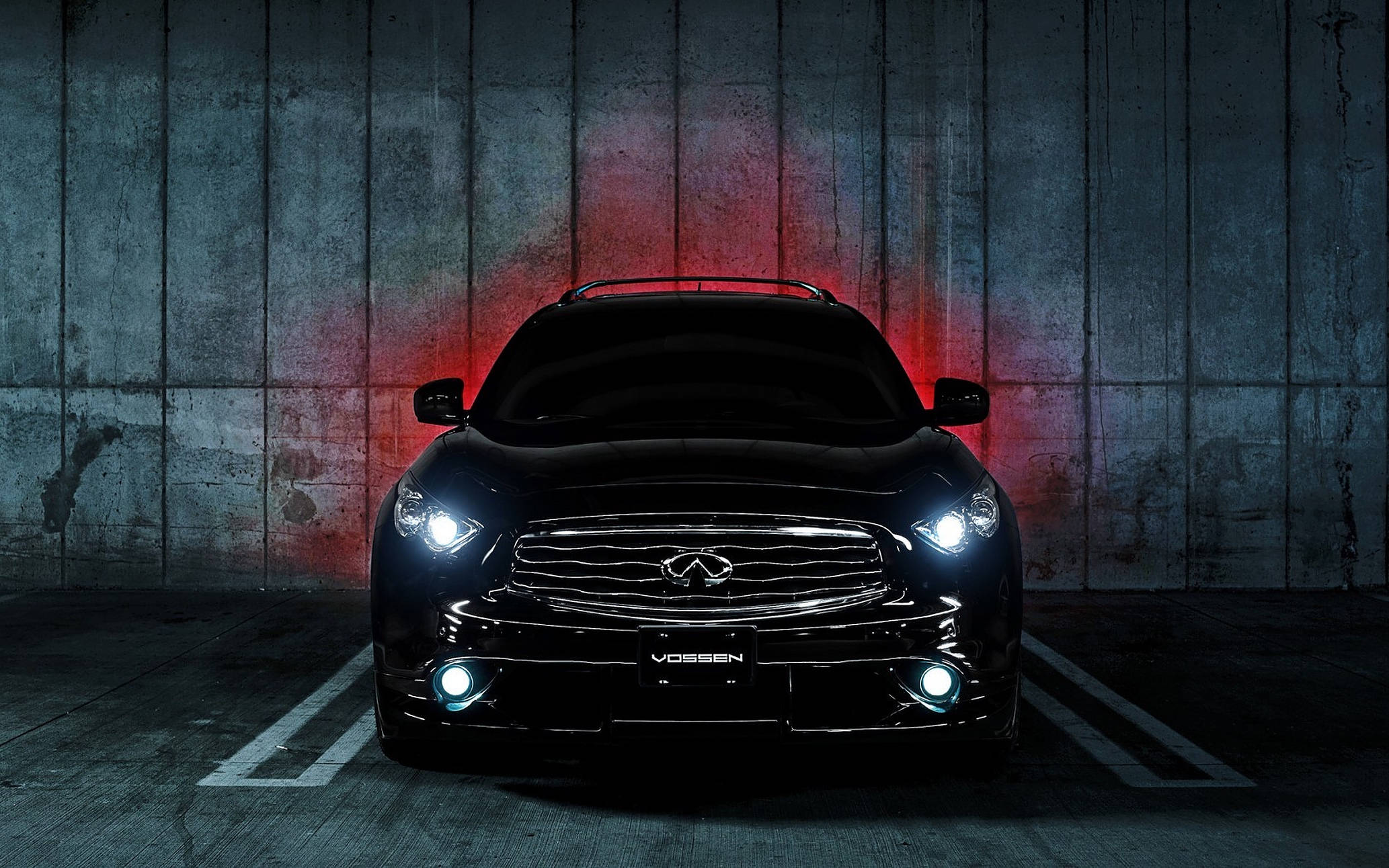 Infiniti 桌布 壁紙 — 一輛時尚的黑色Infiniti SUV，車頭燈發光，停在昏暗的混凝土車庫中，車庫由紅色環境照明照亮。