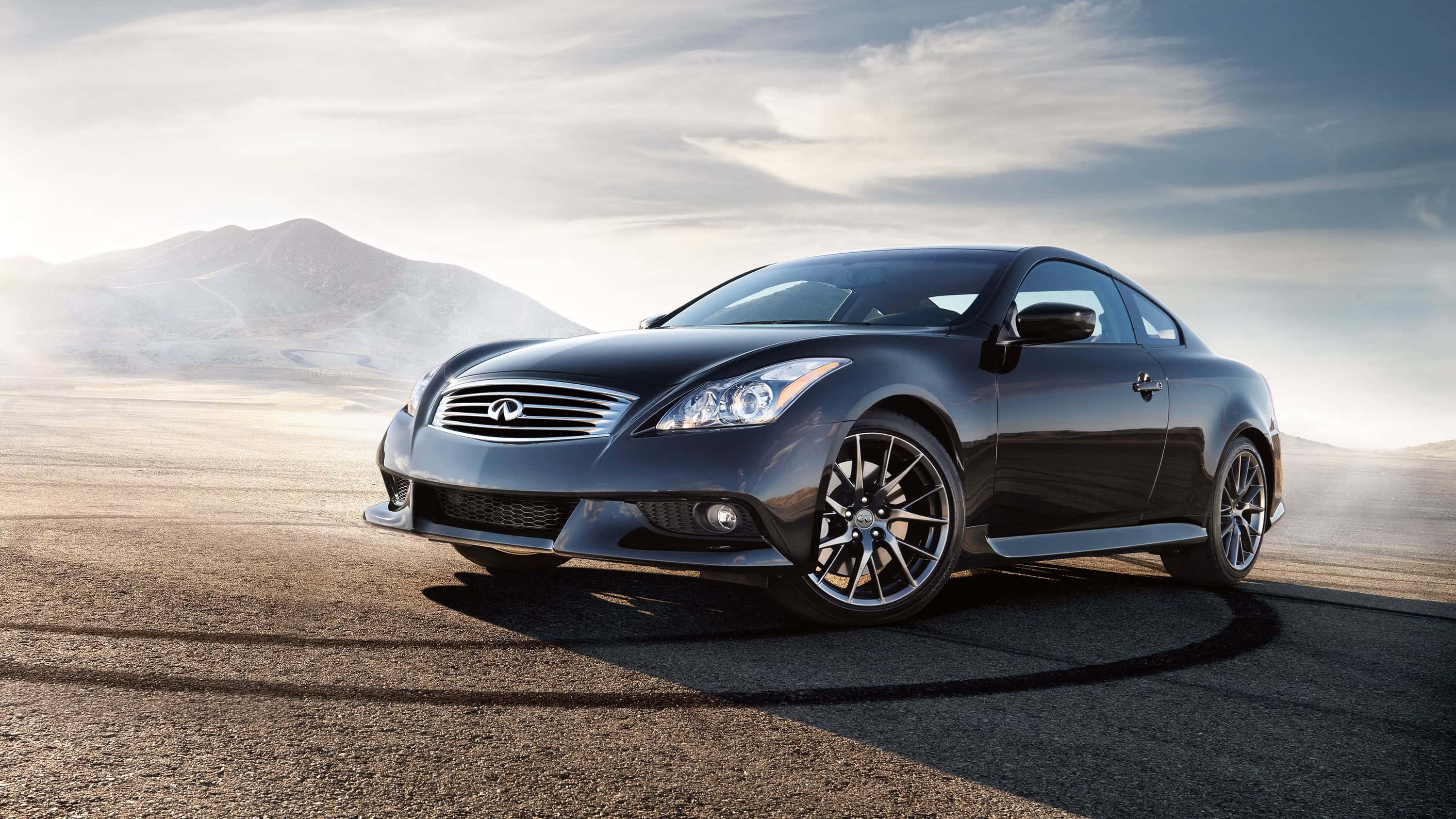 Infiniti Q60 桌布 壁紙 — 一輛時尚的黑色Infiniti轎跑車停在沙漠公路上，遠山在陰天下若隱若現。