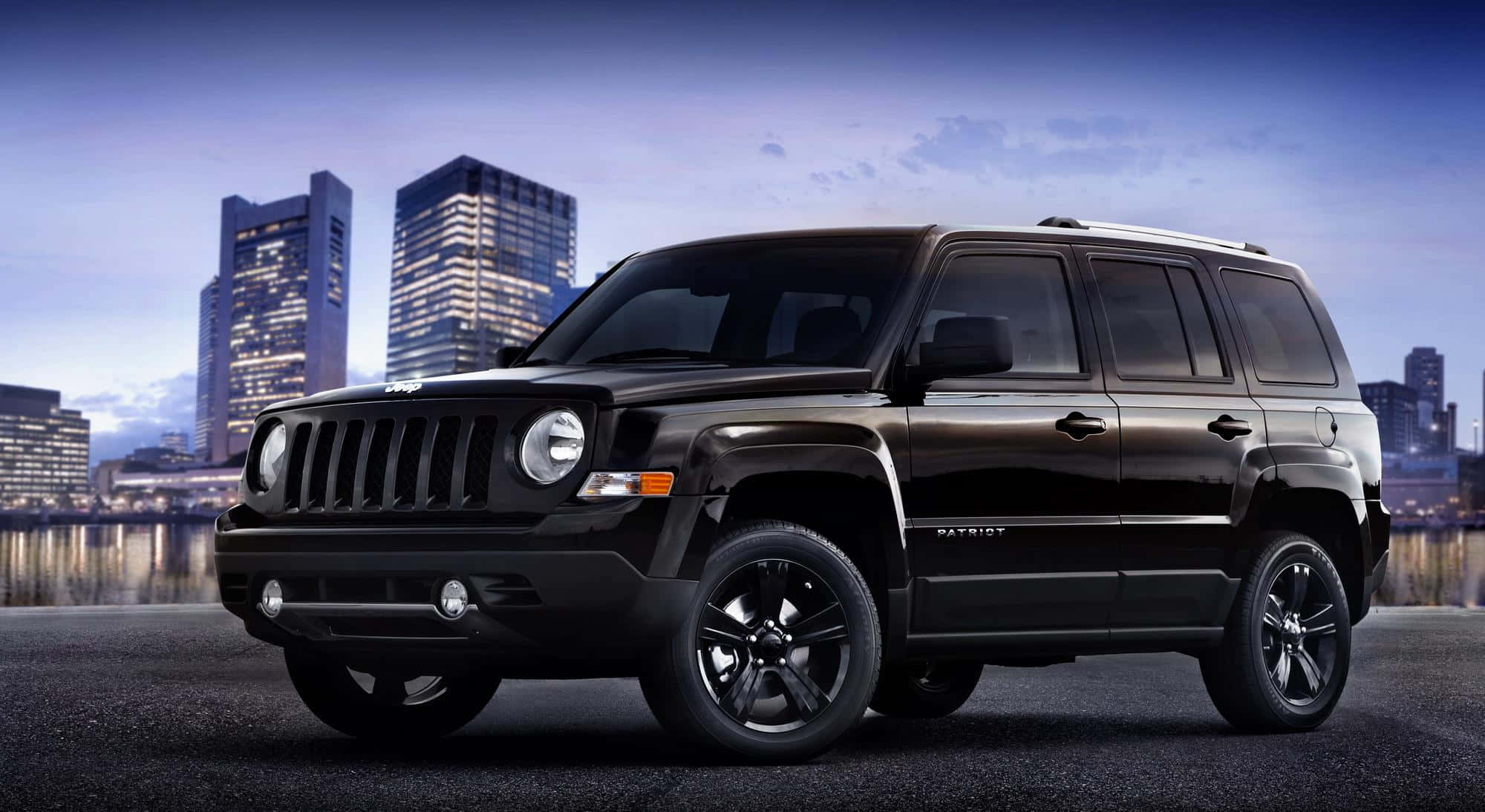 Jeep Patriot 桌布 壁紙 — 一輛時尚的黑色Jeep Patriot SUV停泊在暮色中的城市街道上，背景是燈火通明的摩天大樓。