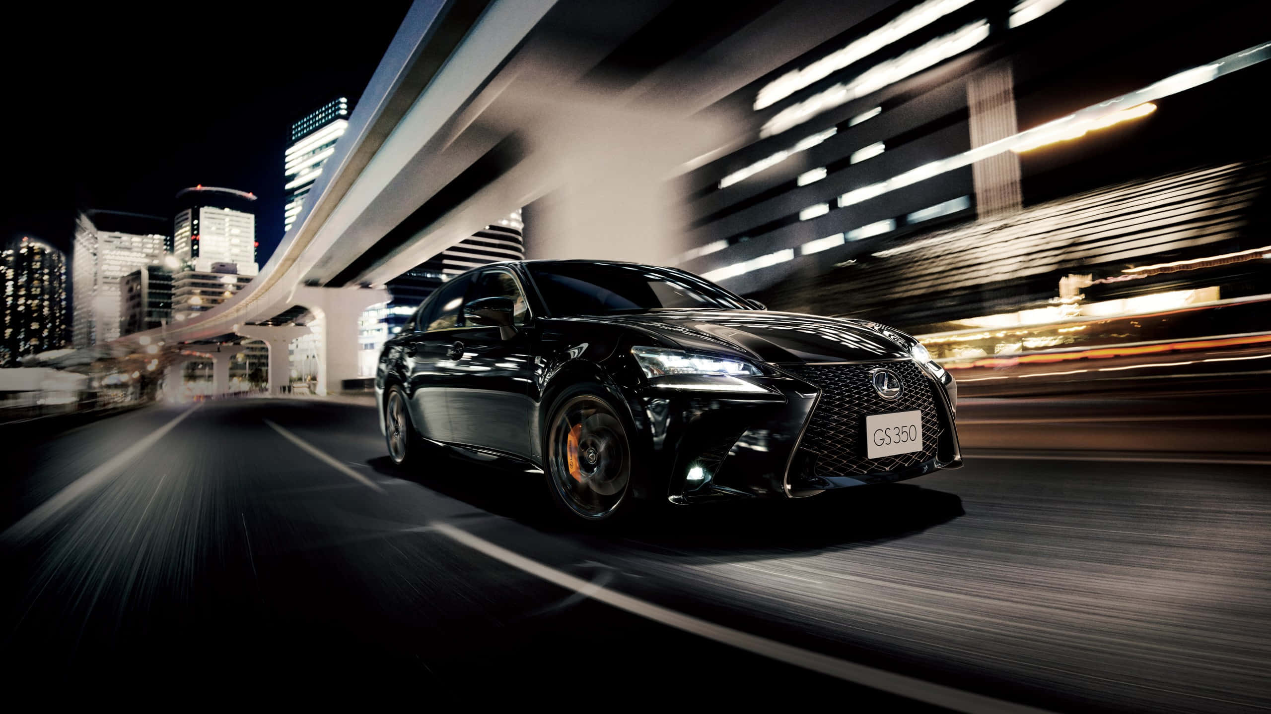Lexus Gs 桌布 壁紙 — 一輛時尚的黑色Lexus GS350在霓虹燈閃爍的都市夜晚高速行駛，動態模糊掠過摩天大樓和天橋。