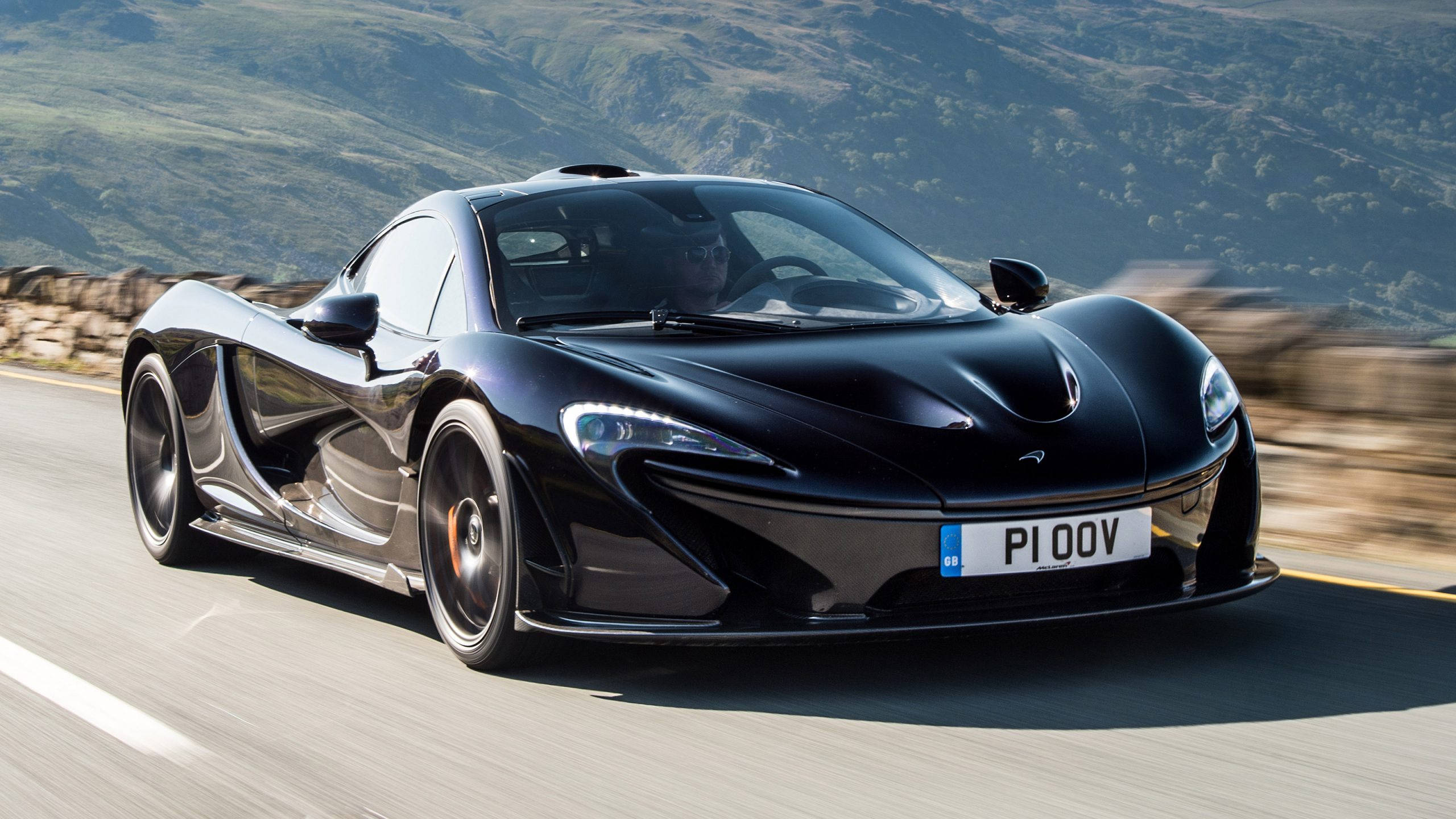 跑車 桌布 壁紙 — 一輛時尚的黑色McLaren P1超級跑車在蜿蜒的山路上奔馳，風景模糊。