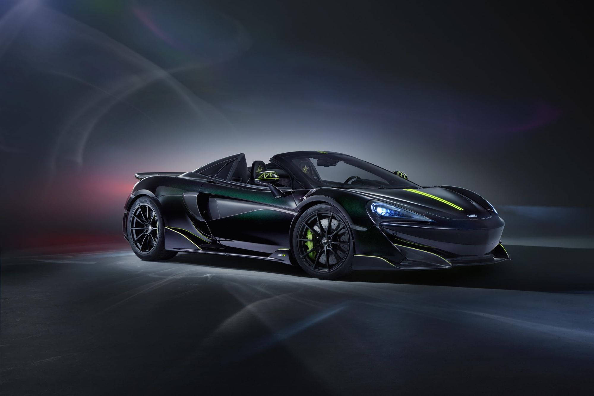 跑車 桌布 壁紙 — 一輛時尚的黑色McLaren跑車，帶有螢光綠色點綴，在戲劇性的工作室燈光下閃耀。