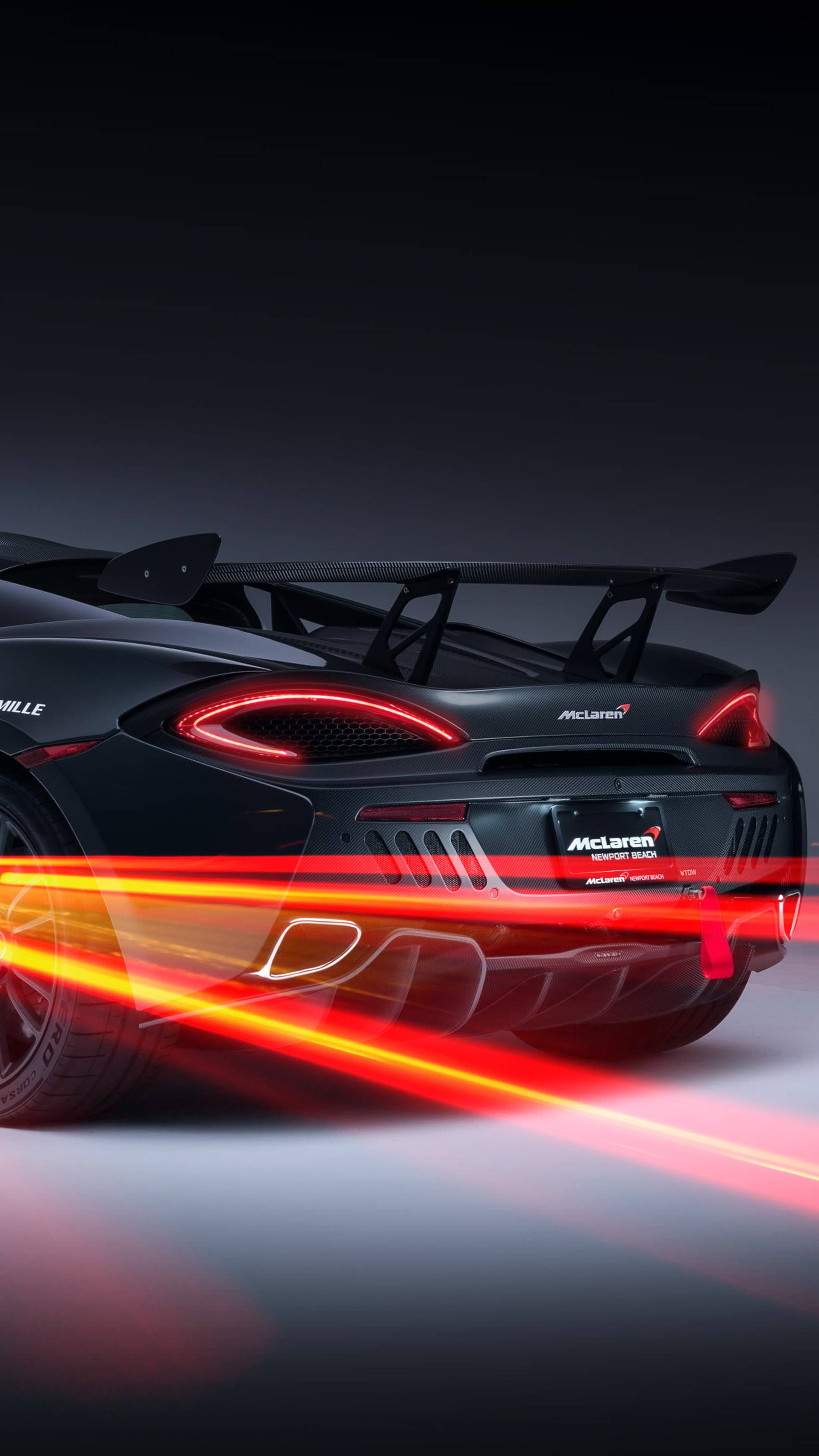 iPhone 桌布 壁紙 — 一輛時尚的黑色McLaren跑車，在黑暗的攝影棚背景下帶有發光的紅色尾燈和動態模糊條紋。