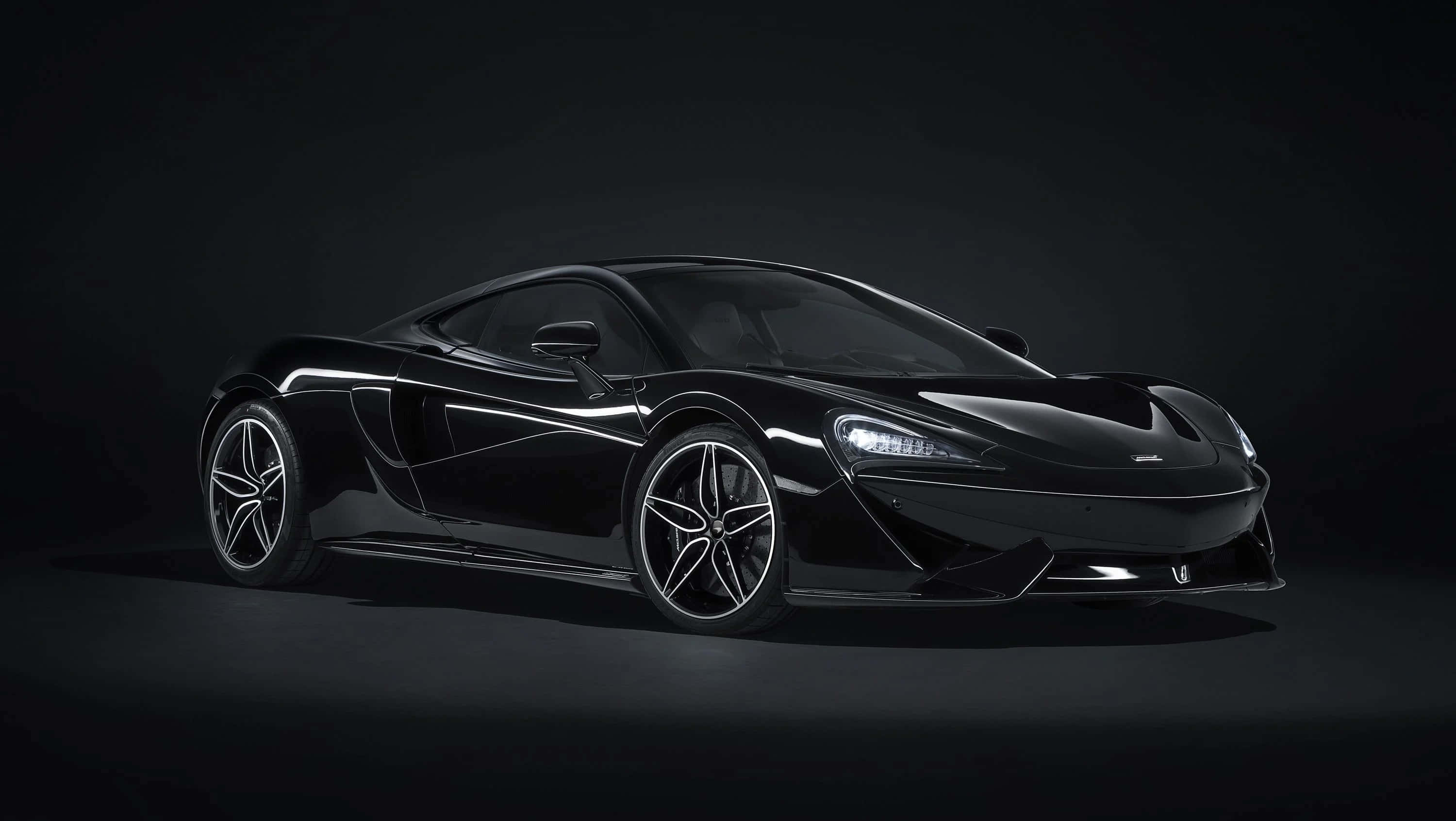 麥拉倫 桌布 壁紙 — 一輛時尚的黑色McLaren跑車在工作室燈光下，在黑暗背景中閃閃發光。