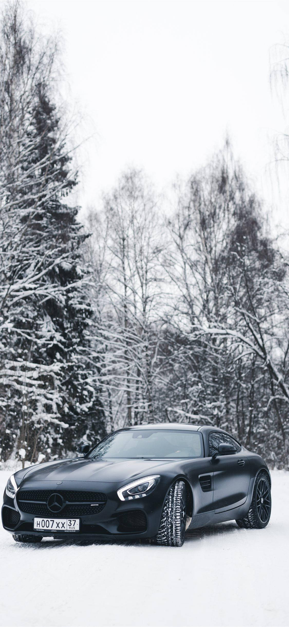X 桌布 壁紙 — 一輛時尚的黑色Mercedes-AMG GT停在雪地上，周圍是冬季被雪覆蓋的樹木。
