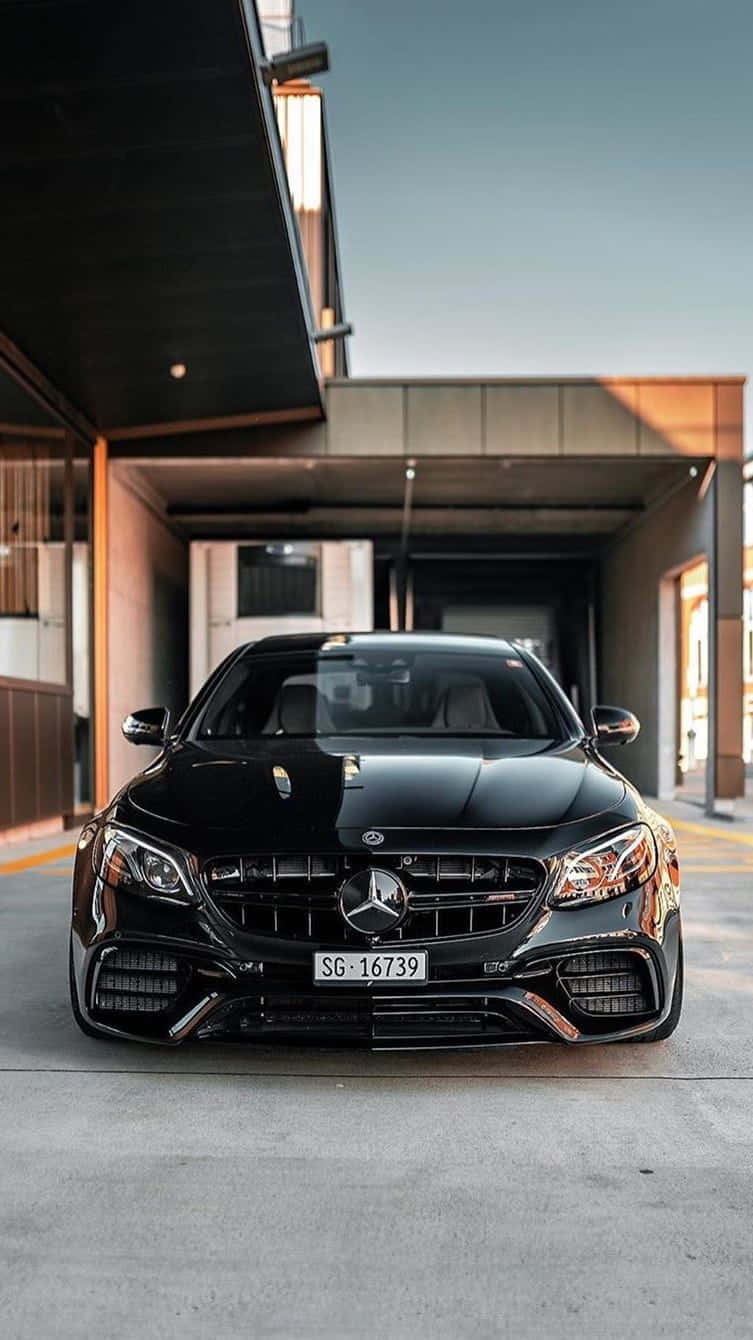 Mercedes Benz Car 桌布 壁紙 — 一輛時尚的黑色Mercedes-AMG停放在現代建築懸挑下，配有溫暖的環境照明。