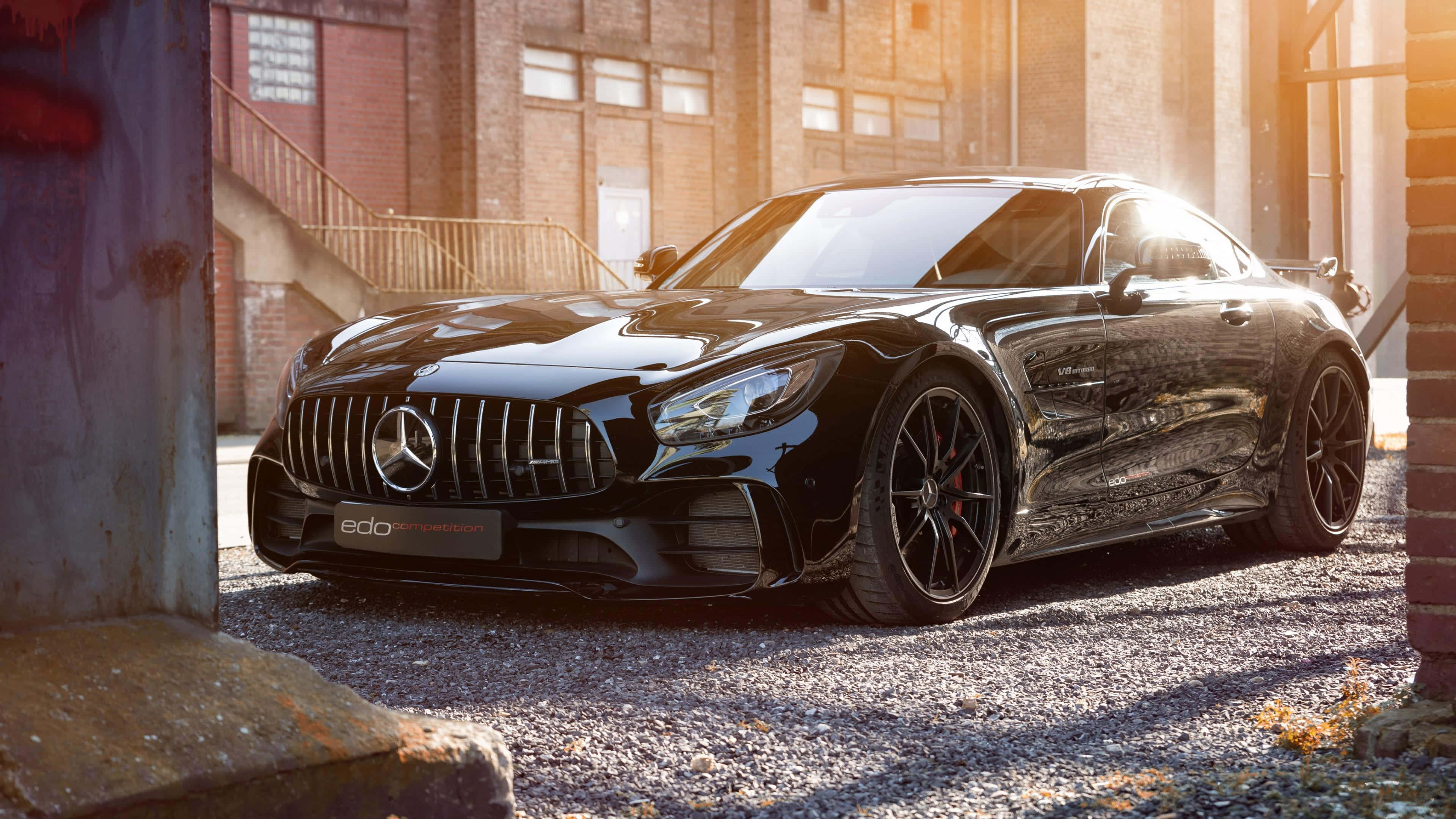 4K 奔馳壁紙 桌布 壁紙 — 一輛時尚的黑色Mercedes-AMG GT Black Series停放在磚牆之間，黃金時段的陽光投射出戲劇性的陰影。