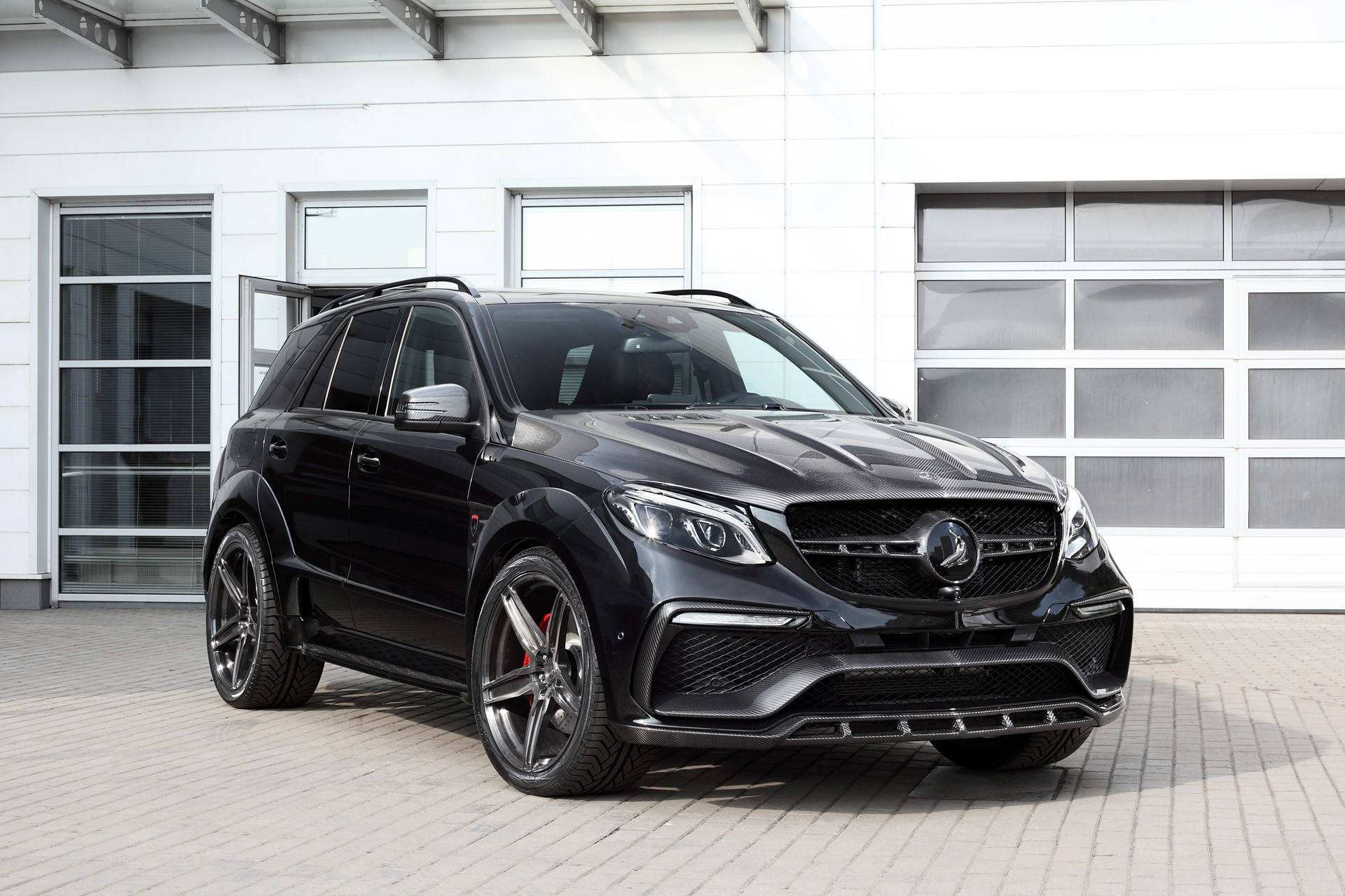 benz 4K 桌布 壁紙 — 一輛時尚的黑色Mercedes-AMG GLE63 SUV，帶有碳纖維飾件和紅色制動卡鉗，停放在現代白色建築前的瓷磚庭院中。