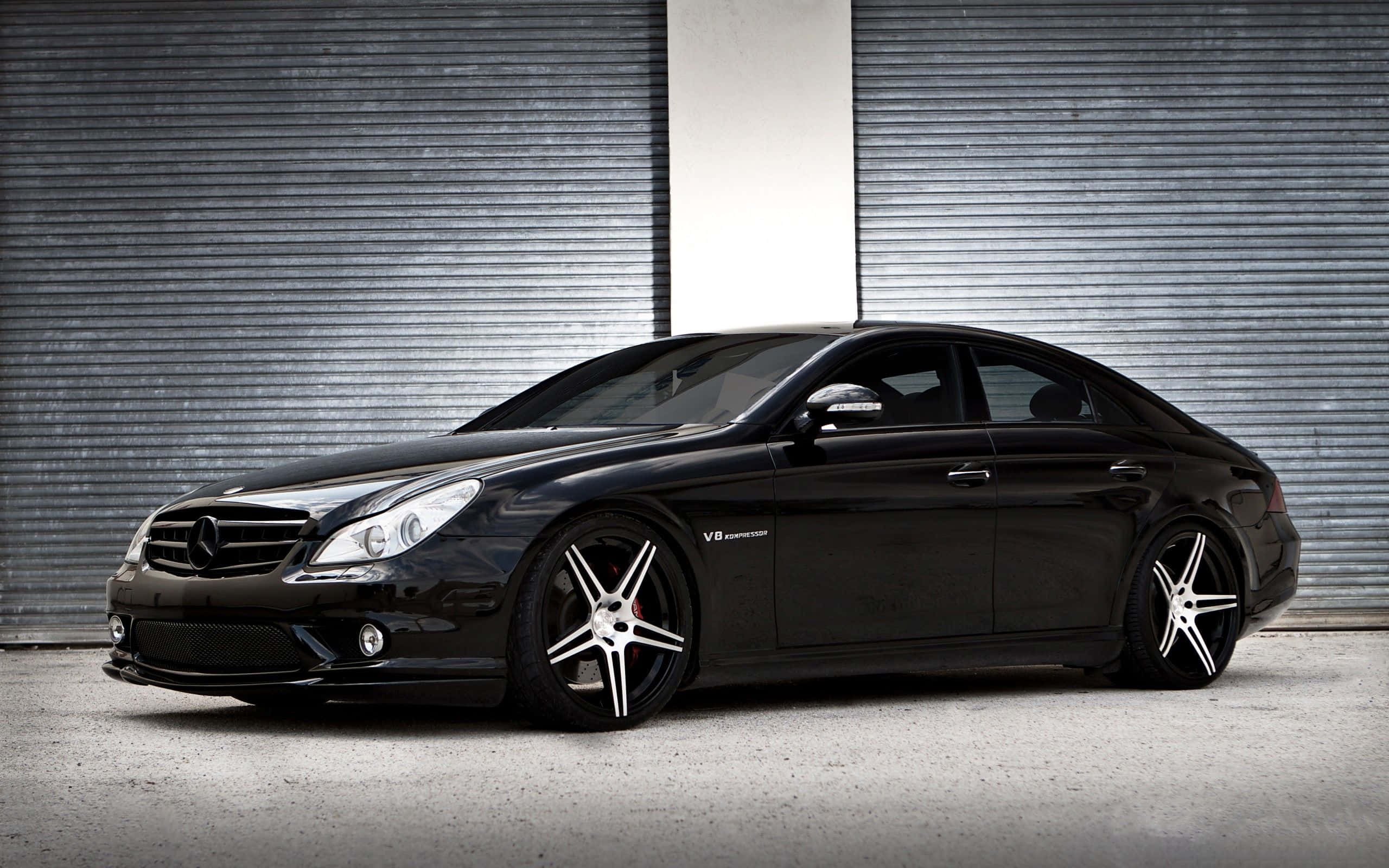 Mercedes 桌布 壁紙 — 一輛時尚的黑色Mercedes-Benz CLS63 AMG配銀色輪圈，停在波紋金屬車庫門前。