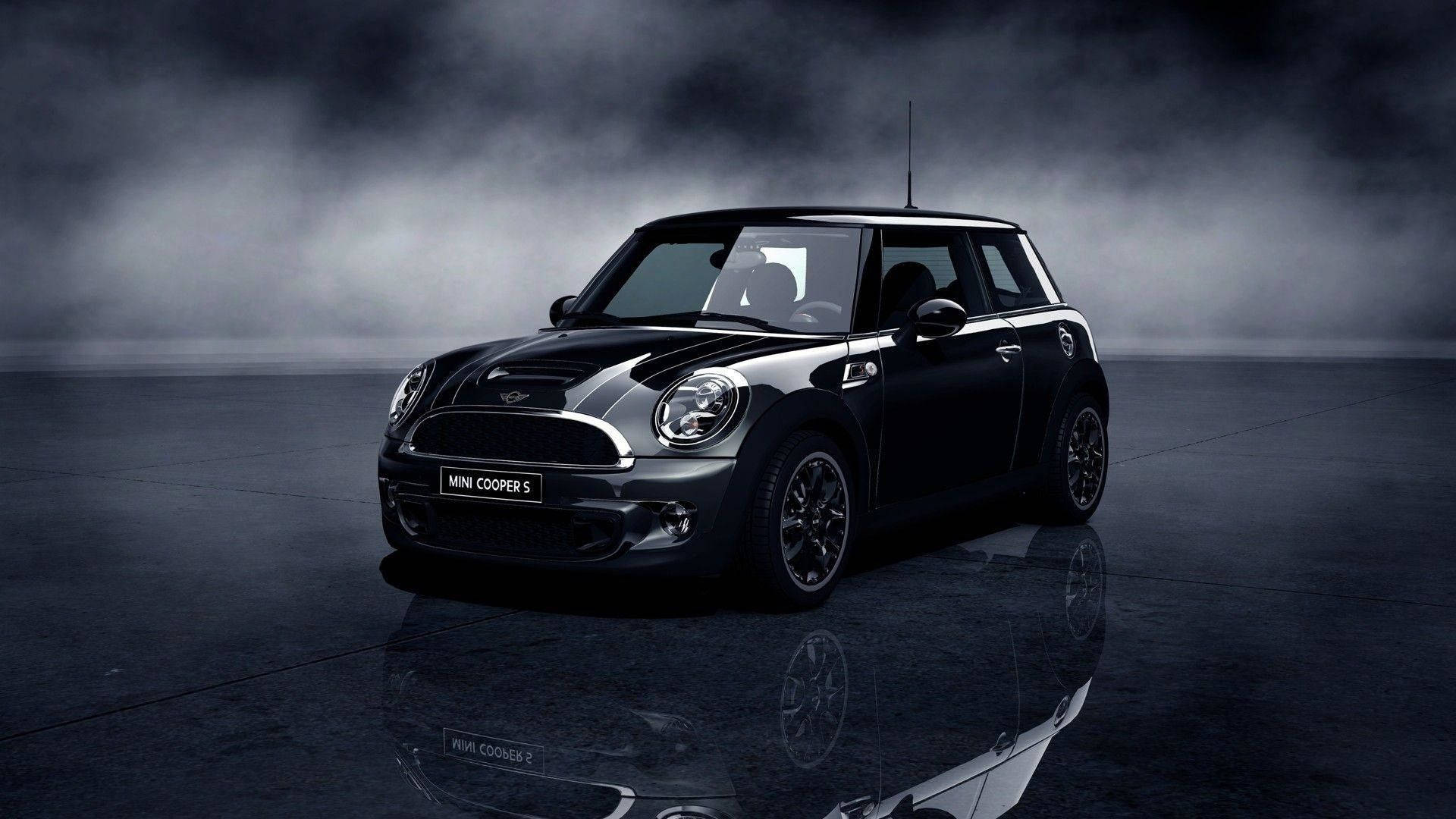 Mini Cooper 桌布 壁紙 — 一輛時尚的黑色MINI Cooper S在戲劇性燈光下，在反光的濕滑路面上閃閃發光，上方有霧濛濛的烏雲。