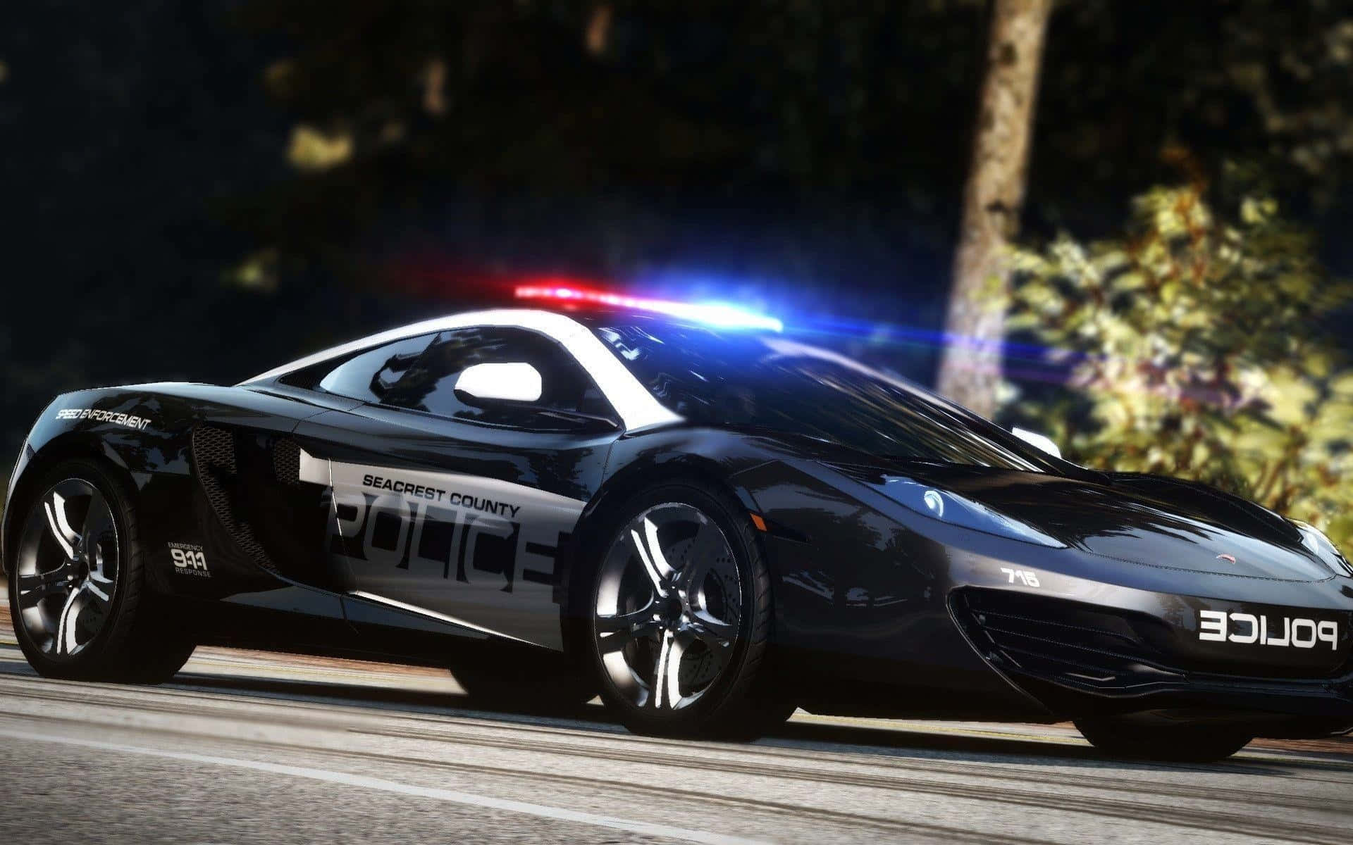 Police Car 桌布 壁紙 — 一輛時尚的黑色Seacrest County警用跑車，閃爍著紅藍燈光，在夜間沿著綠樹成蔭的道路疾馳。