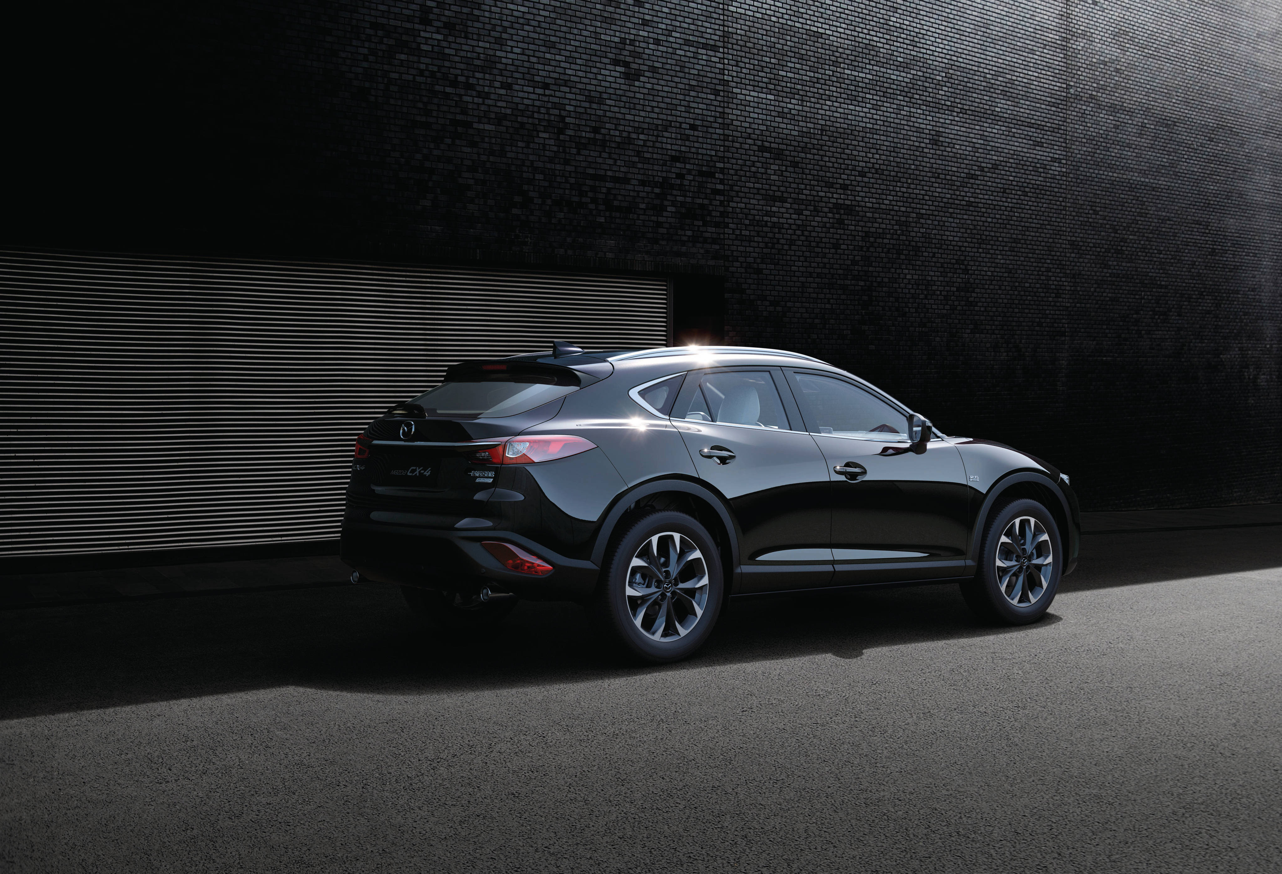 Mazda 桌布 壁紙 — 一輛時尚的黑色SUV停靠在深色磚牆前，戲劇性的聚光燈凸顯其曲線和合金輪圈。