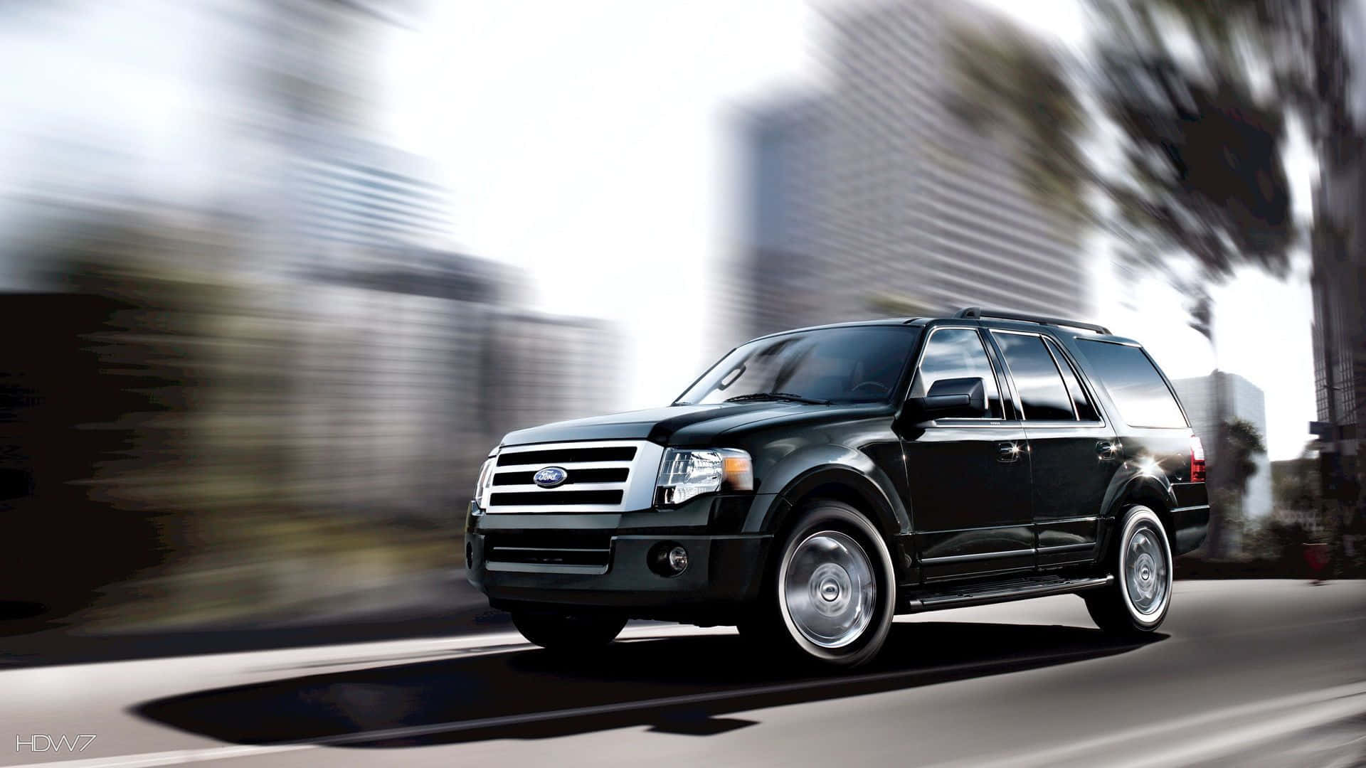 Ford Expedition 桌布 壁紙 — 一輛時尚的黑色SUV在模糊的城市街道上飛馳，高樓大廈和樹木從旁掠過。