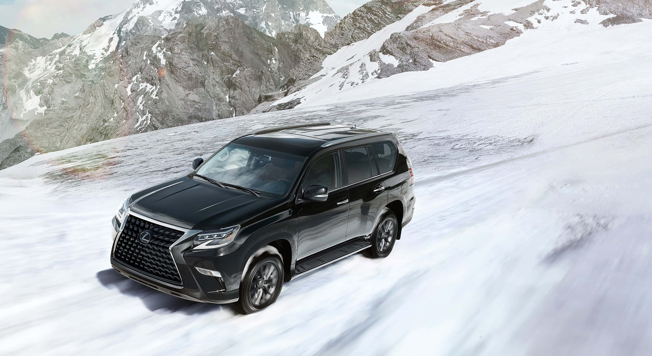 Lexus Gx 460 桌布 壁紙 — 一輛時尚的黑色SUV在深雪中行駛於山隘，背景是崎嶇的雪峰。
