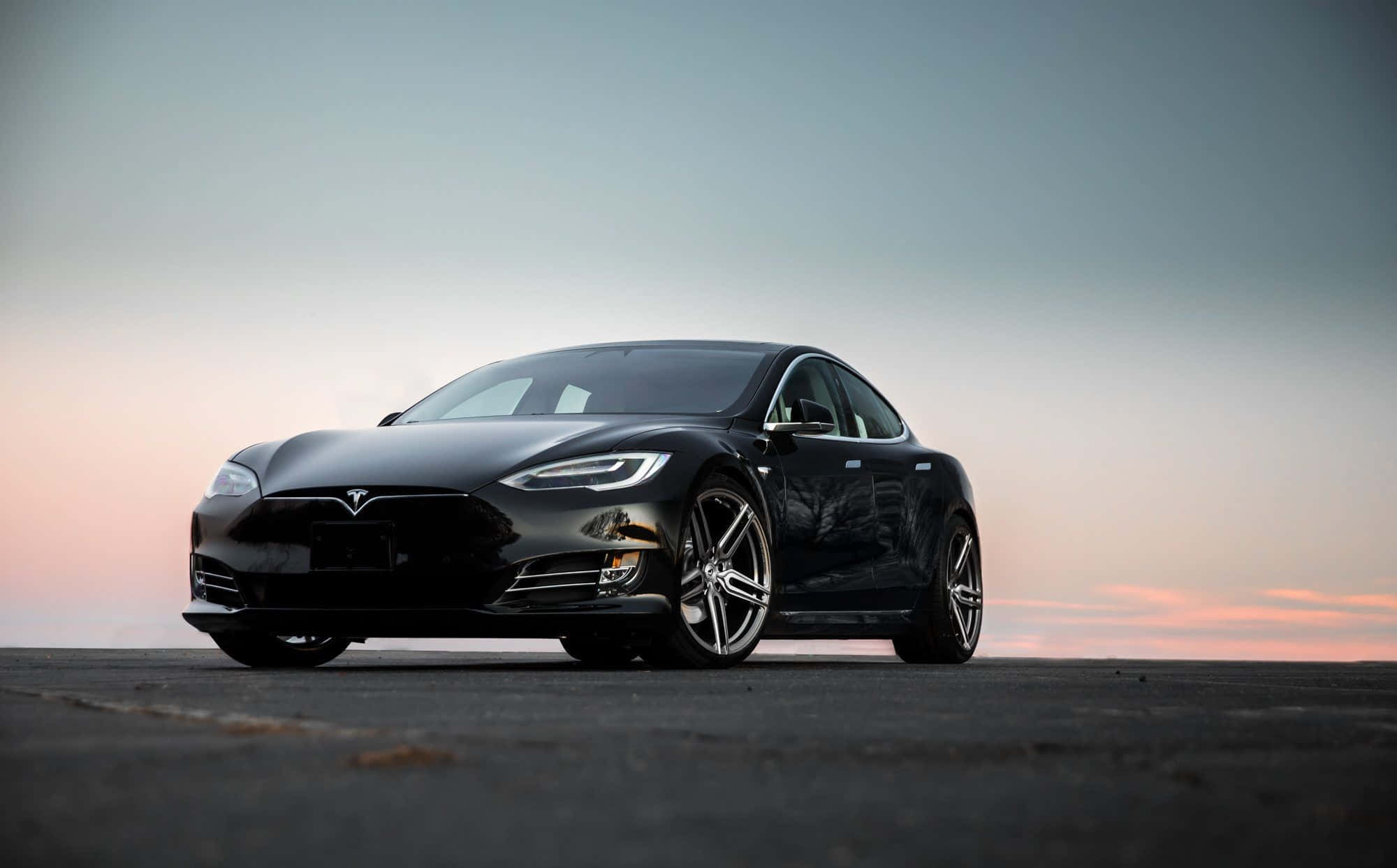 Hybrid Car 桌布 壁紙 — 一輛時尚的黑色Tesla Model S停在瀝青路面上，天空呈現柔和的粉紅和藍色暮色。