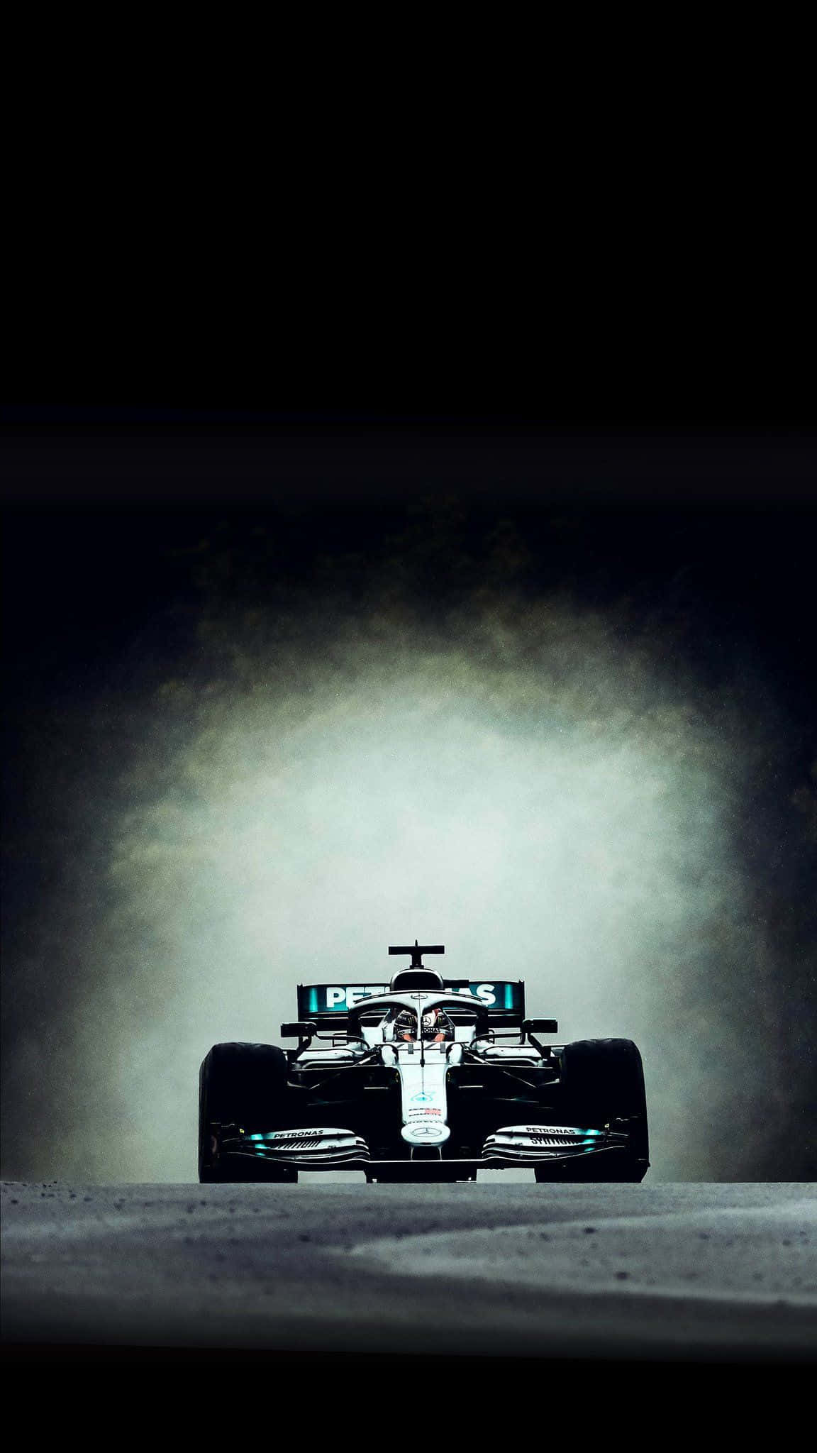 Formula 1 iPhone 桌布 壁紙 — 一輛時尚的黑色一級方程式賽車在黑暗賽道的聚光燈下從薄霧中出現。