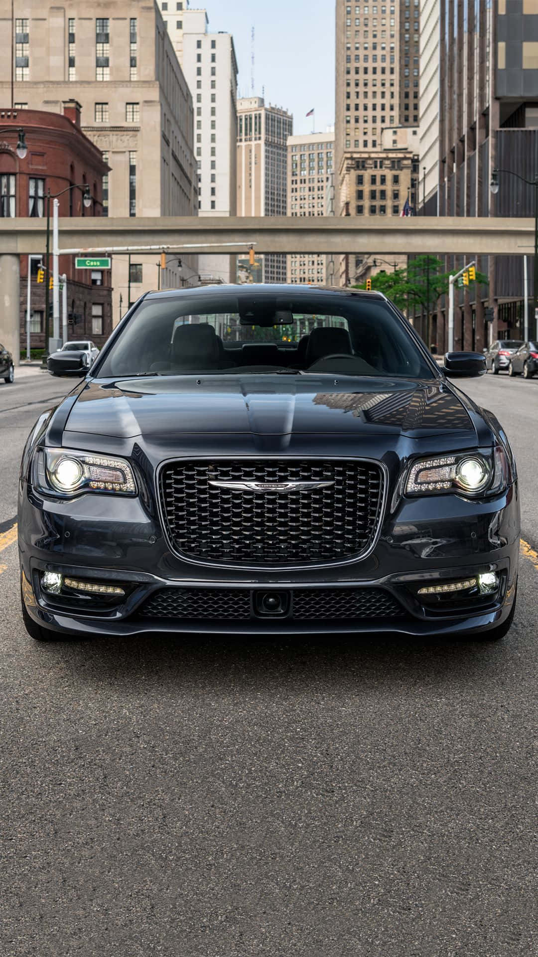 Chrysler 300 桌布 壁紙 — 一輛時尚的黑色克萊斯勒300轎車在由高樓大廈和天橋構成的城市街道上向前行駛。