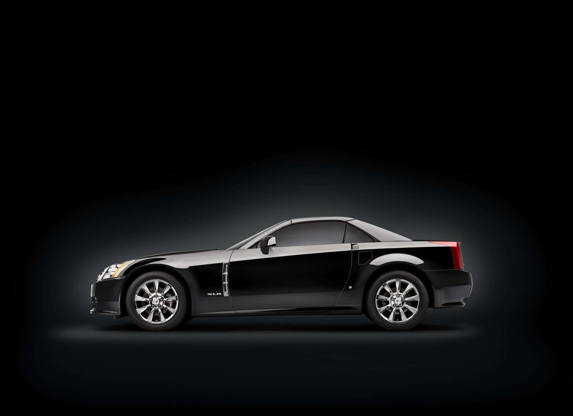 Cadillac Xlr 桌布 壁紙 — 一輛時尚的黑色凱迪拉克XLR跑車在暗色漸變背景下的攝影棚燈光中閃耀。