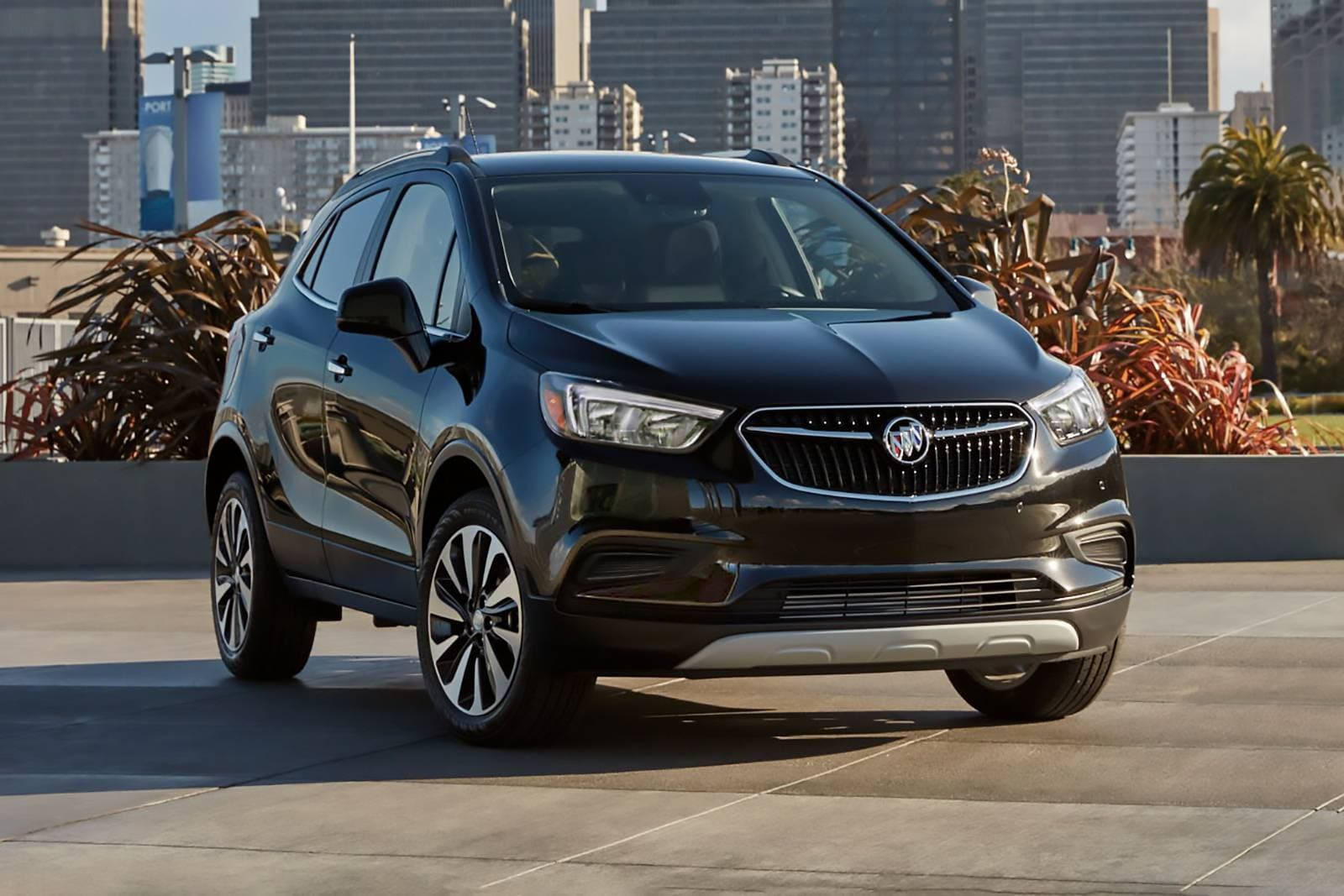 Buick 桌布 壁紙 — 一輛時尚的黑色別克SUV停在屋頂露台上，背景是現代城市天際線和棕櫚樹。