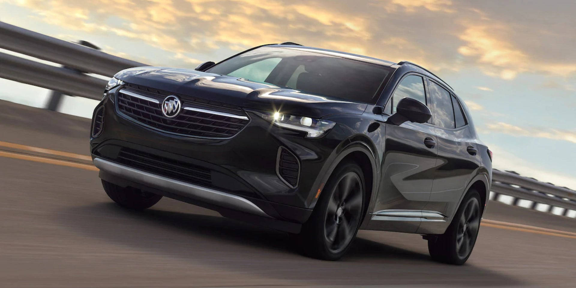 Buick 桌布 壁紙 — 一輛時尚的黑色別克SUV在日落時分的高速公路上飛馳，金色的雲彩映照在其光亮的車身上。