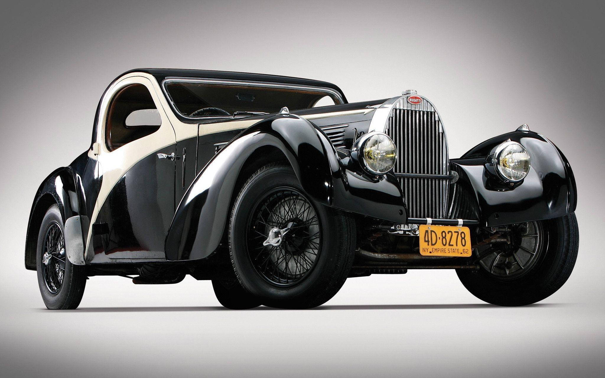 Vintage Car 桌布 壁紙 — 一輛時尚的黑色和奶油色復古布加迪雙門轎車，配備鋼絲輪轂和鍍鉻格柵，置於中性灰色工作室背景前。