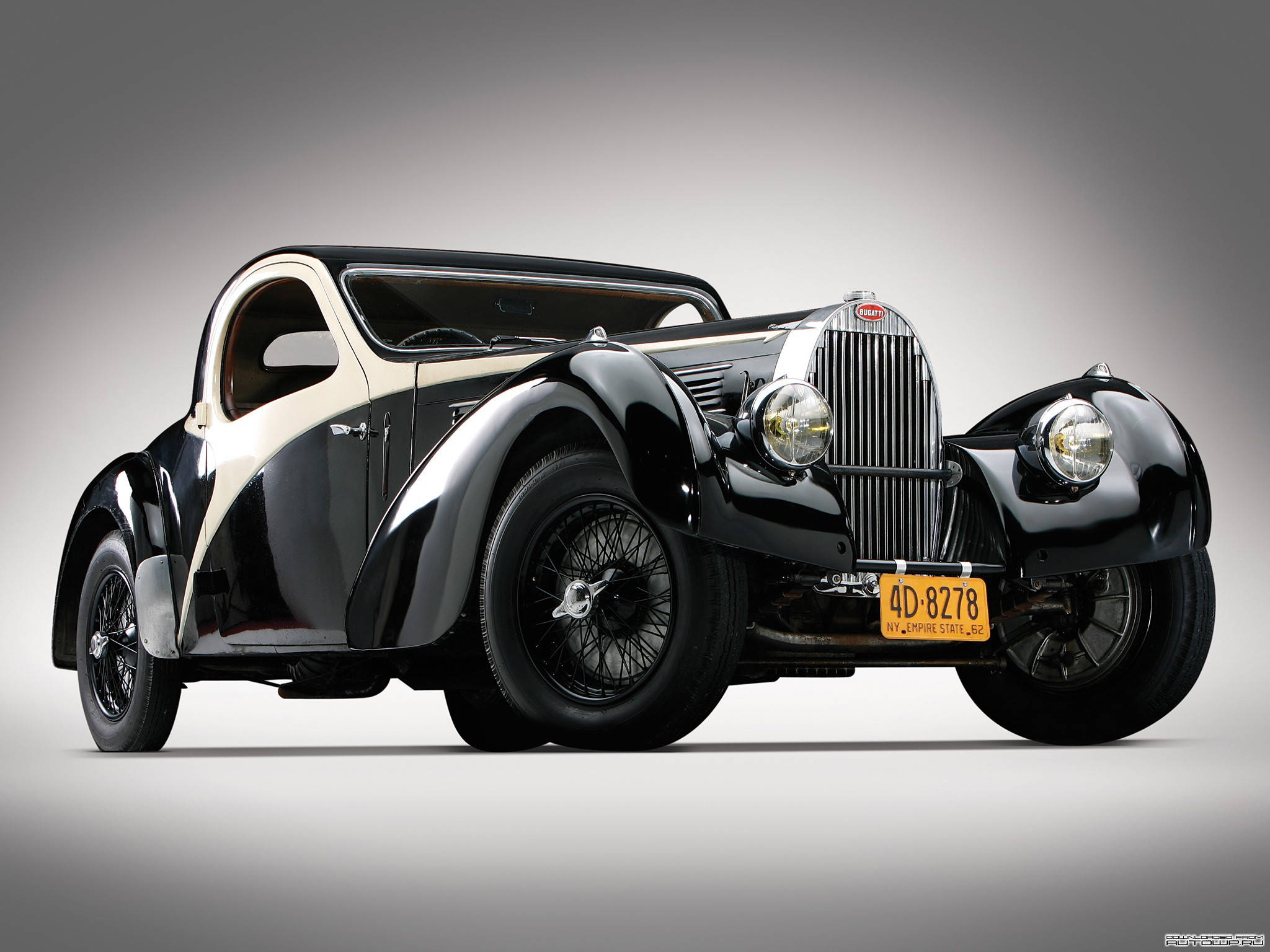 bugatti iPhone 桌布 壁紙 — 一輛時尚的黑色和奶油色復古布加迪轎跑車，配備鋼絲輪轂和鍍鉻格柵，在漸變灰色工作室背景前擺姿勢。