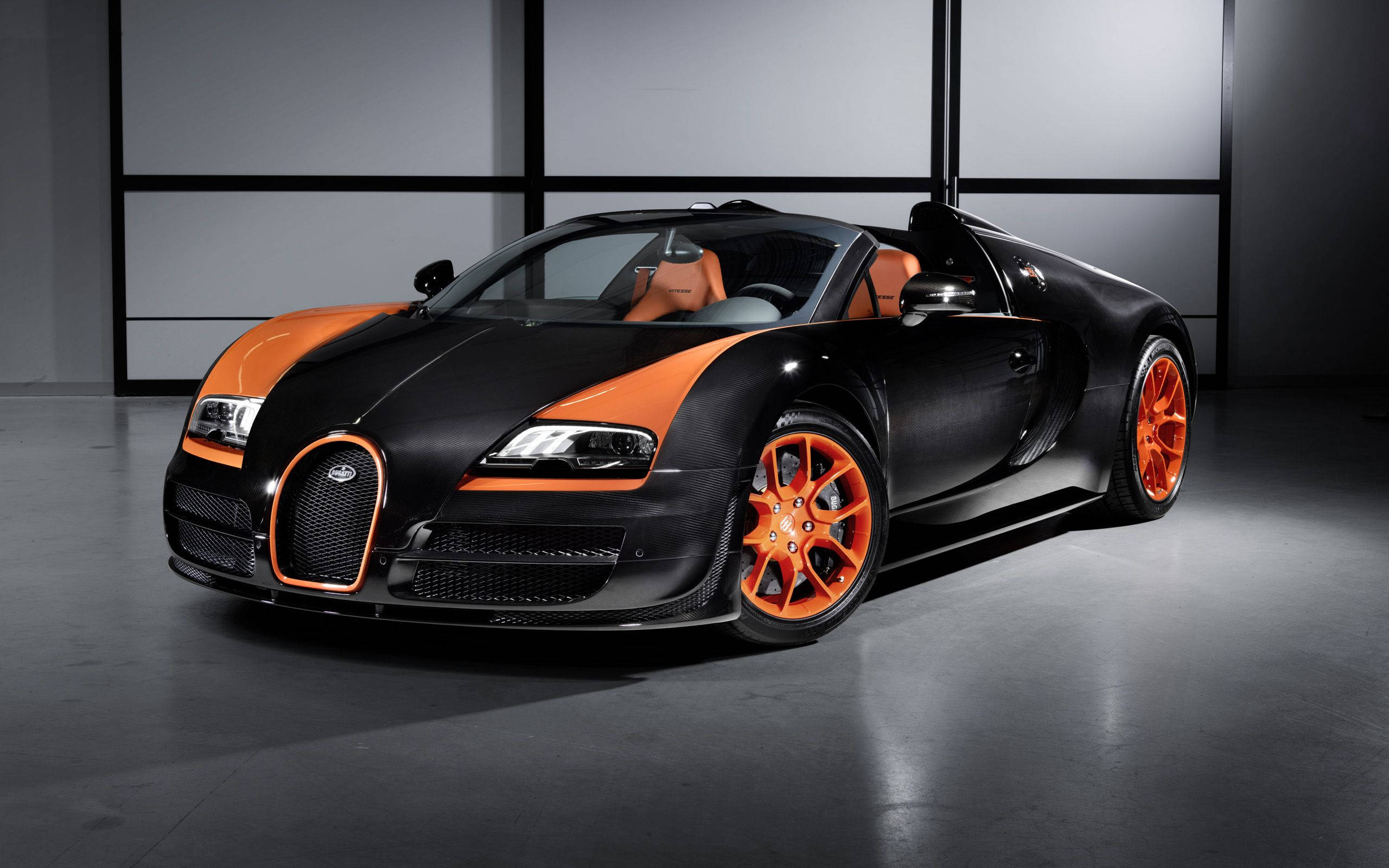 布加迪 桌布 壁紙 — 一輛時尚的黑色和橙色Bugatti Veyron超級跑車，配備橙色輪圈和內飾，在簡約的工作室中展示，帶有戲劇性的燈光。