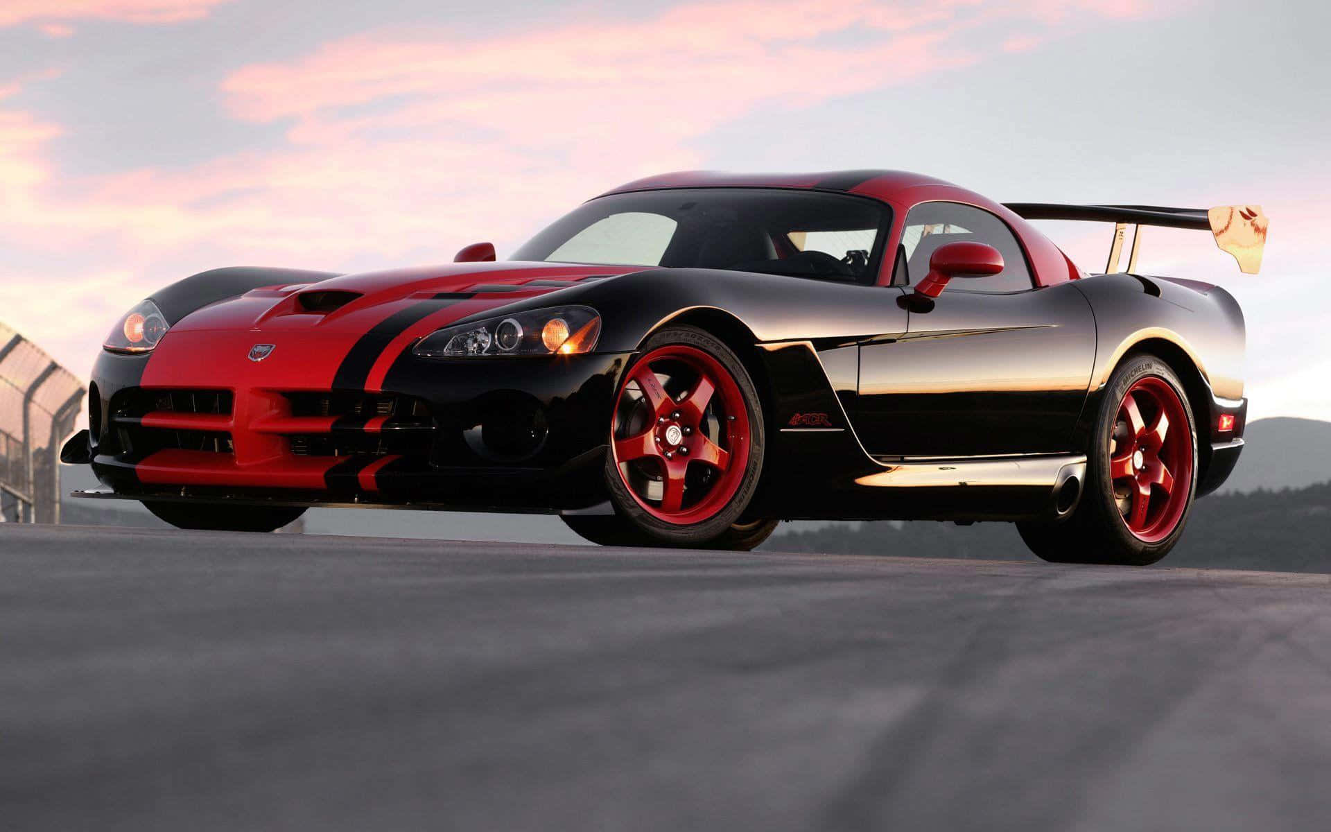 Dodge 桌布 壁紙 — 一輛時尚的黑色和紅色Dodge Viper跑車，配紅色輪圈，停泊在日落時分的賽道上。