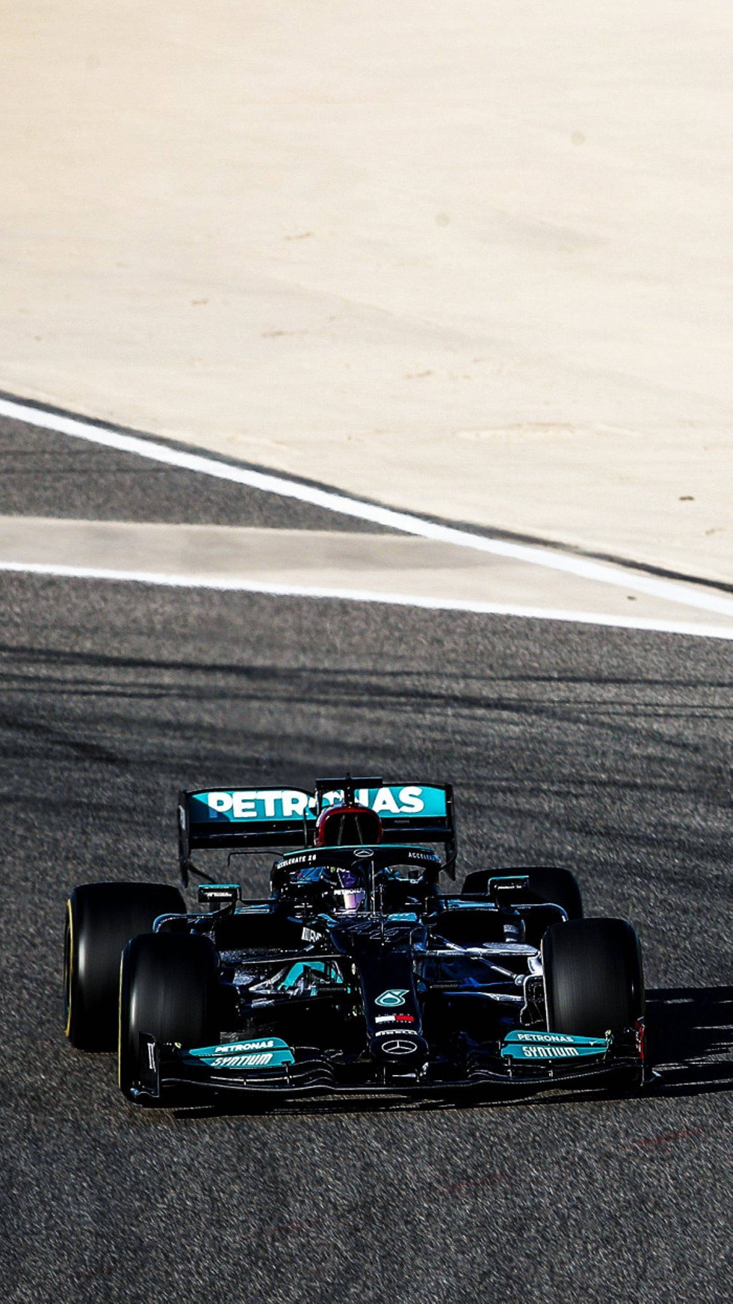 F1 桌布 壁紙 — 一輛時尚的黑色和藍綠色一級方程式賽車沿著陽光普照的瀝青賽道緊貼著白色路緣行駛。