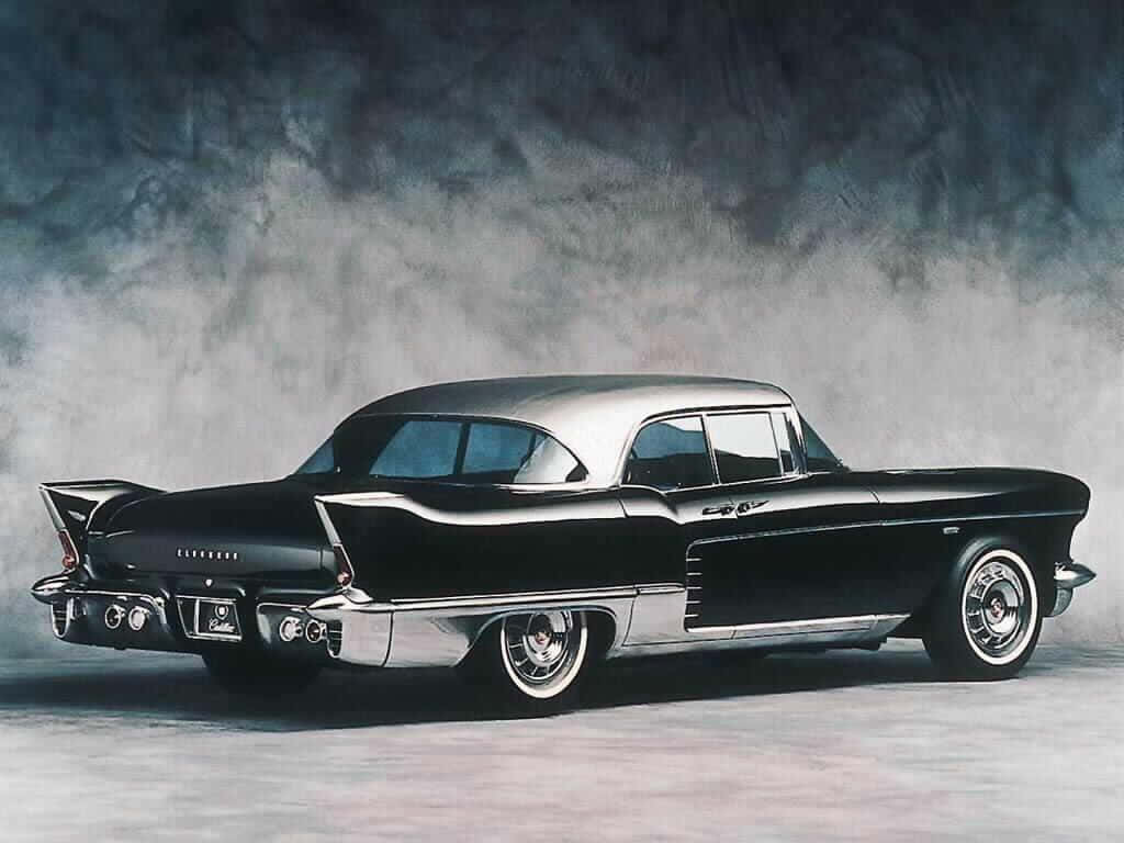 Cadillac 桌布 壁紙 — 一輛時尚的黑色和銀色1959年凱迪拉克Coupe DeVille，帶有鍍鉻飾邊和尾鰭，在煙霧瀰漫的灰色工作室背景前擺好姿勢。