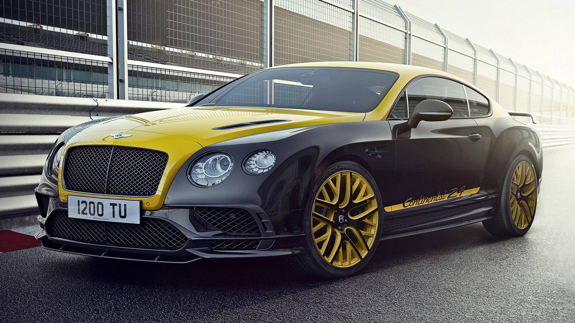 bentley HD 桌布 壁紙 — 一輛時尚的黑色和黃色 Bentley Continental GT3 賽車停在賽道上，背景有護欄和圍欄。