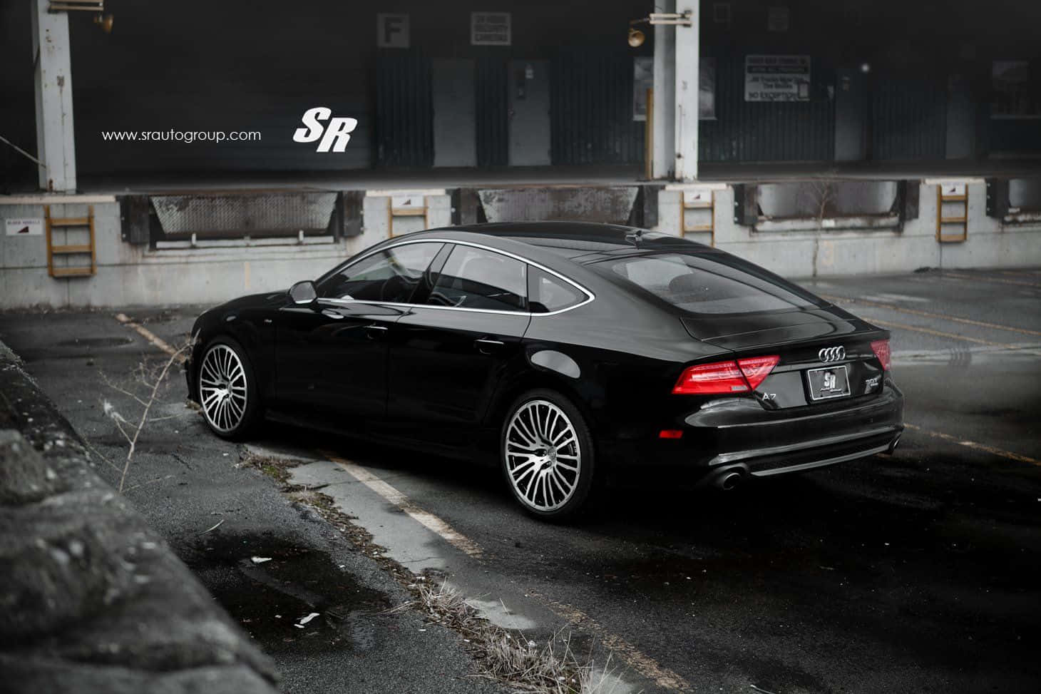 Audi S7 桌布 壁紙 — 一輛時尚的黑色奧迪A7轎車停放在粗糙的城市地段，地面潮濕，背景是工業建築。