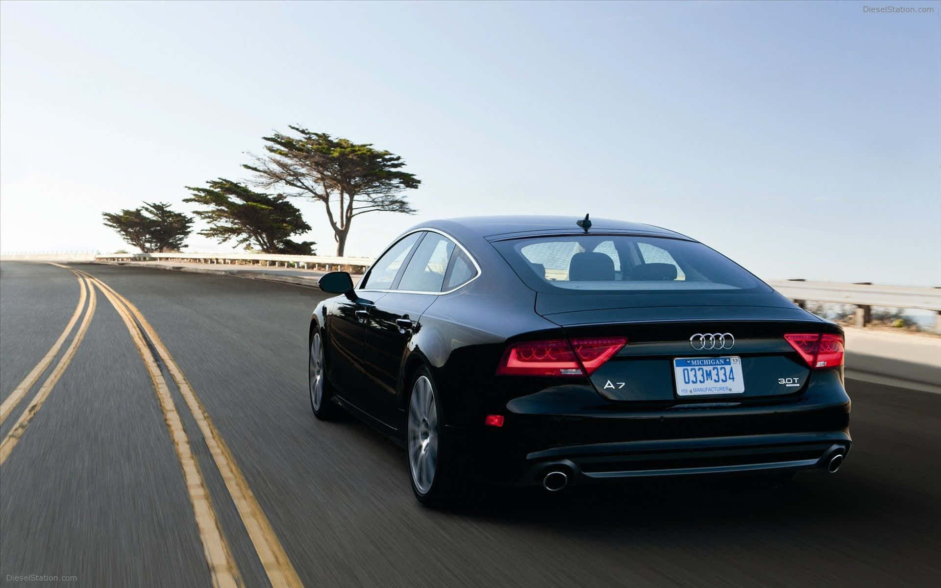 Audi S7 桌布 壁紙 — 一輛時尚的黑色奧迪A7轎車在晴朗的藍天下沿著海岸高速公路行駛，帶有模糊的動態效果。
