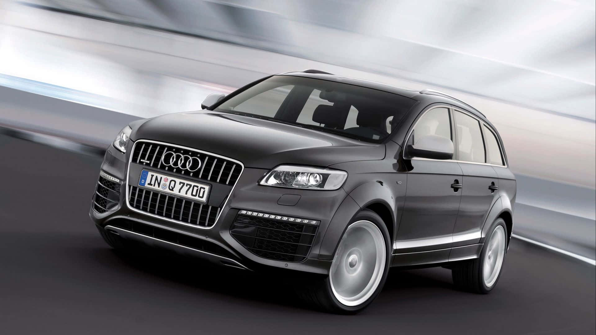 Audi Q7 桌布 壁紙 — 一輛時尚的黑色奧迪Q7 SUV在背景中帶著動態模糊條紋向前飛馳。