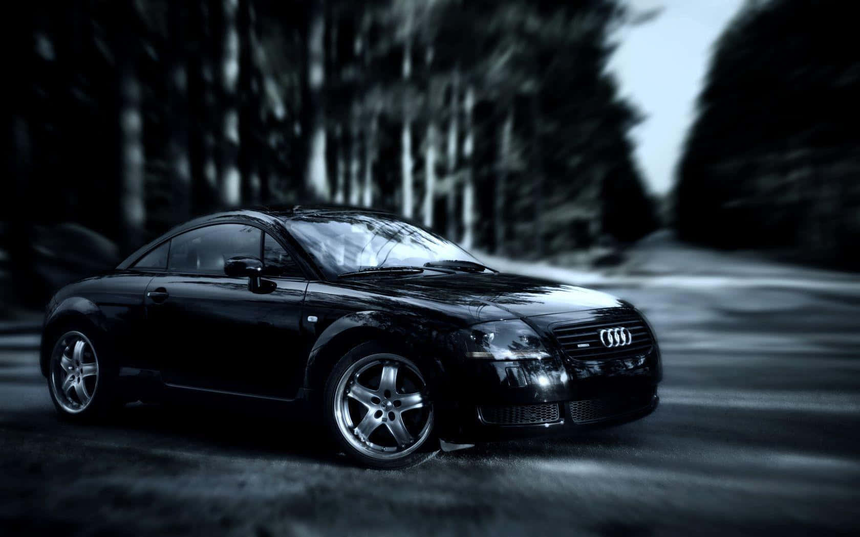 Audi Tt 桌布 壁紙 — 一輛時尚的黑色奧迪TT雙門跑車在迷霧籠罩的森林道路上，於陰鬱的暮色天空下滑行。