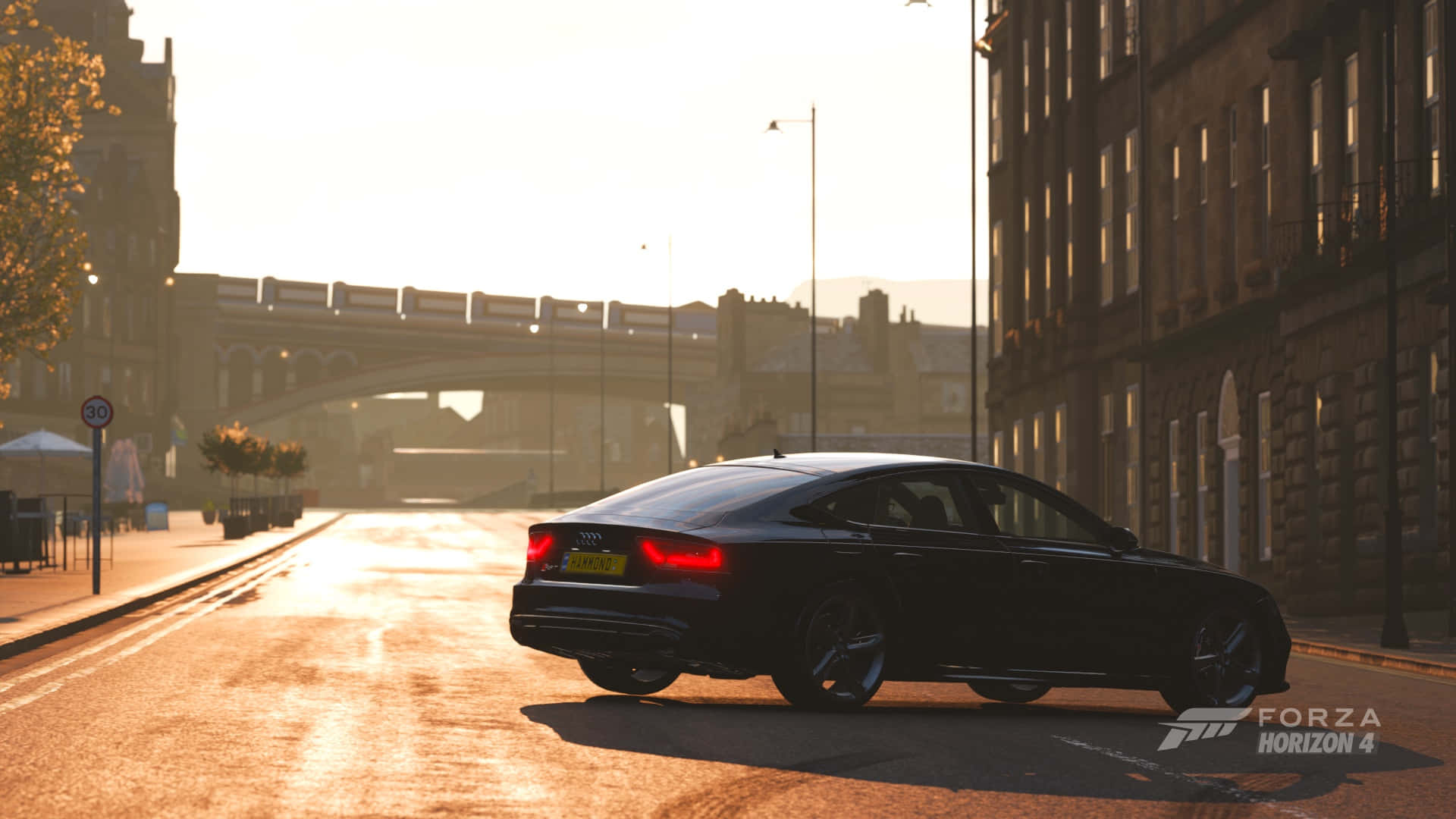 1920x1080 Forza Horizon 4 桌布 壁紙 — 一輛時尚的黑色奧迪轎車在陽光明媚的黃金時段沿著城市街道滑行，溫暖的光線反射在潮濕的路面和歷史建築上。