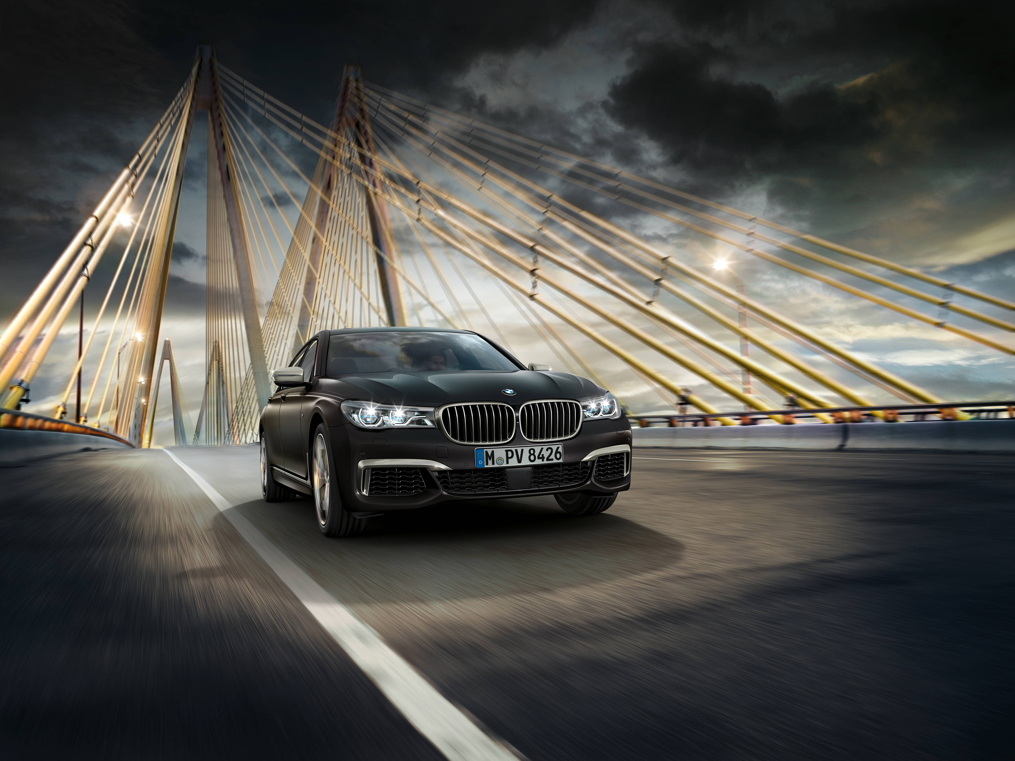 BMW 動圖 桌布 壁紙 — 一輛時尚的黑色寶馬轎車在戲劇性的暴風雨天空下，疾馳過現代斜張橋。