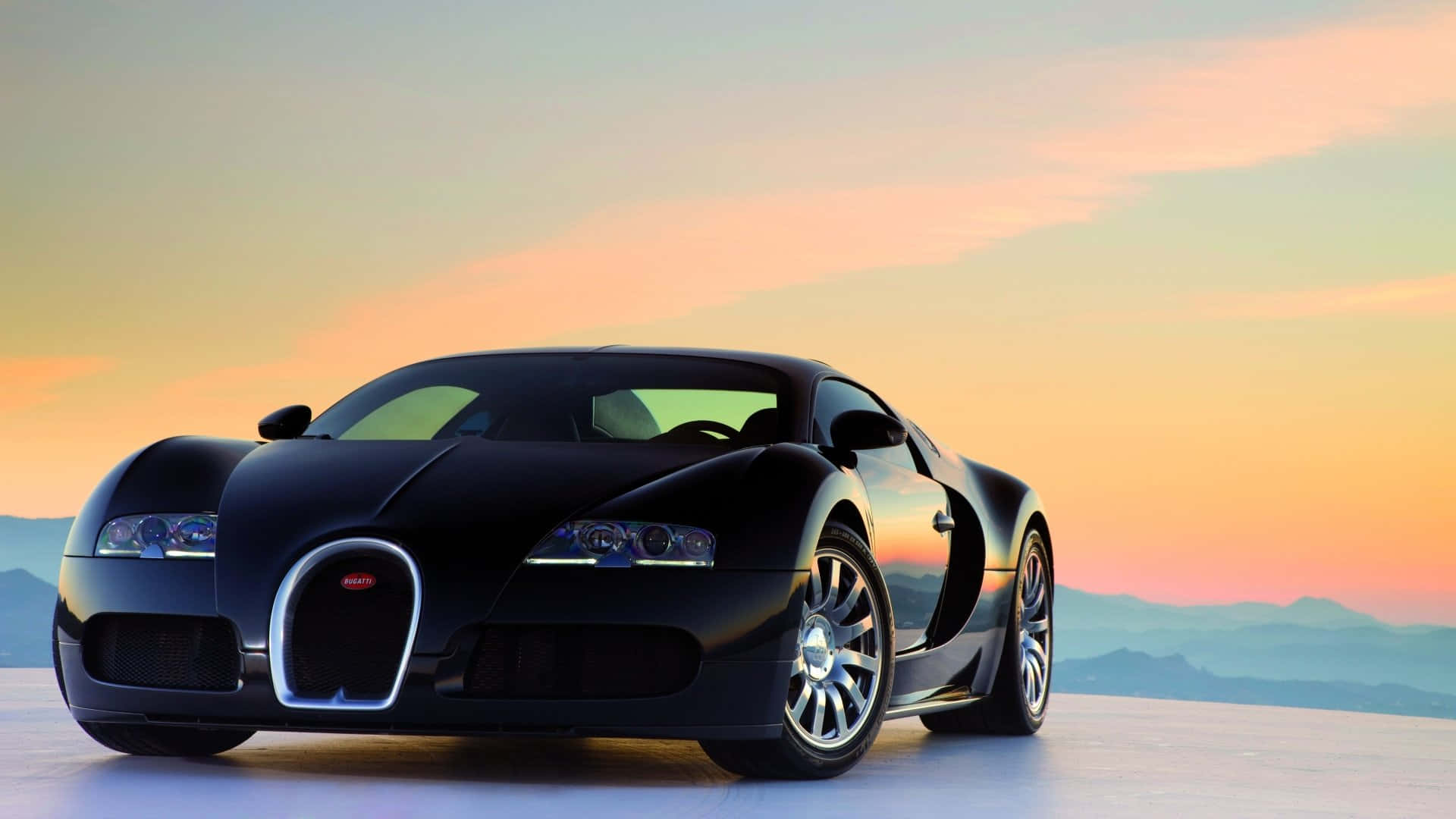 Best Bugatti 桌布 壁紙 — 一輛時尚的黑色布加迪超級跑車在 vibrant 的日落天空下閃閃發光，背景是遠山。