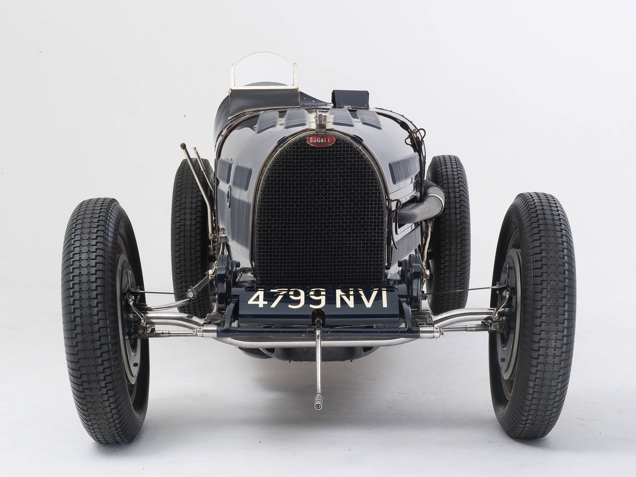 bugatti iPhone 桌布 壁紙 — 一輛時尚的黑色復古Bugatti賽車，帶有鍍鉻裝飾和車牌4799 NVI，在純白背景下蓄勢待發。