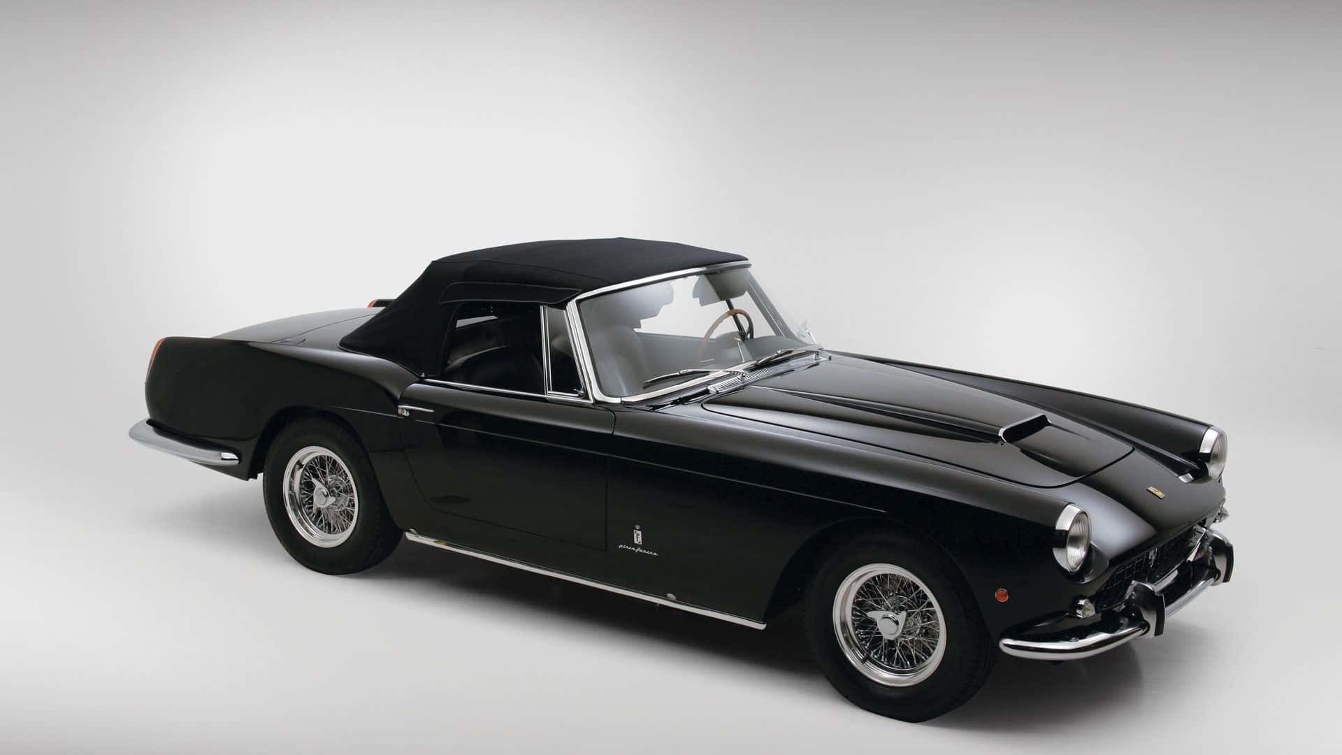 Black And White Vintage Car 桌布 壁紙 — 一輛時尚的黑色復古敞篷跑車，帶有鍍鉻裝飾和鋼絲輪圈，擺放在極簡白色工作室背景前。