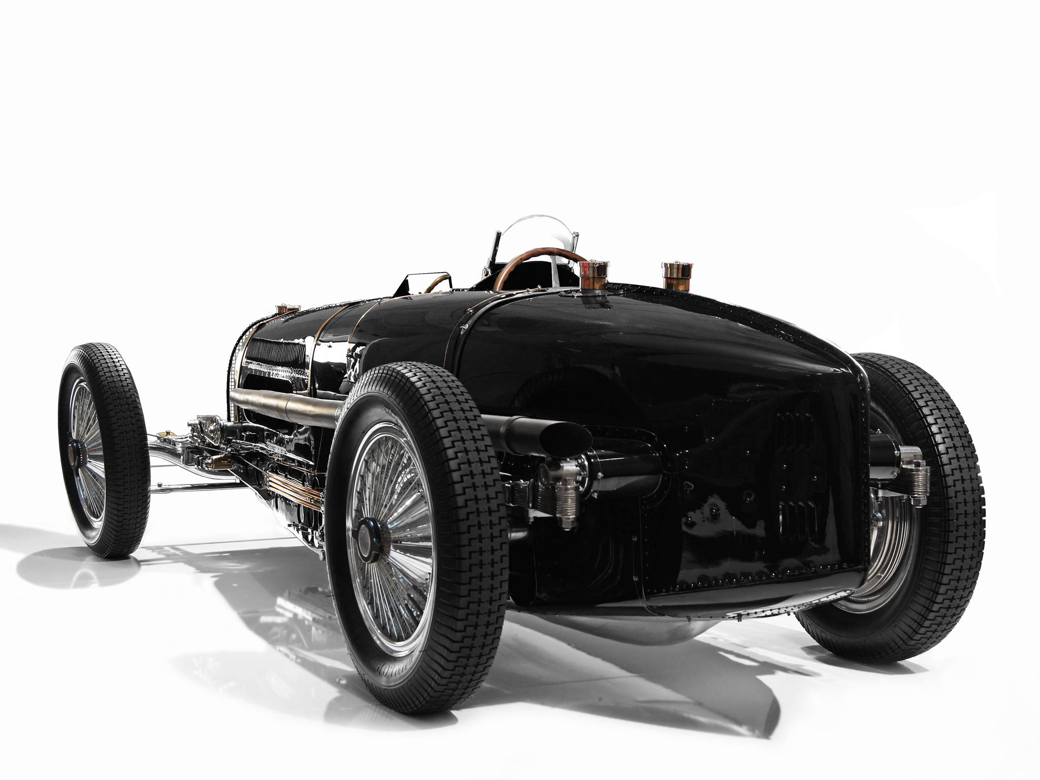 bugatti iPhone 桌布 壁紙 — 一輛時尚的黑色復古賽車，帶有外露的機械結構和鋼絲輪圈，在純白色背景的攝影棚燈光下閃閃發光。