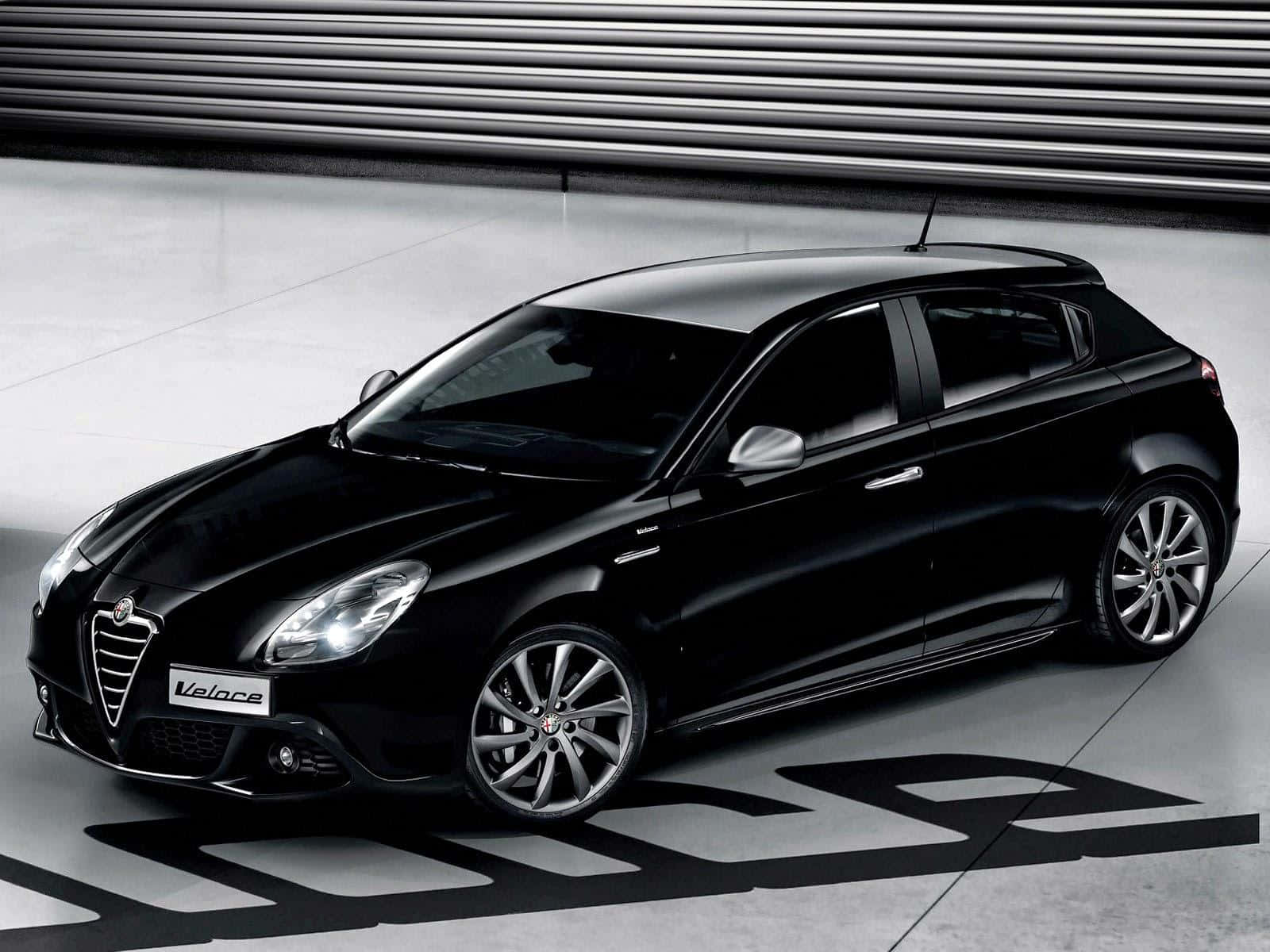 Alfa Romeo Giulietta 桌布 壁紙 — 一輛時尚的黑色愛快羅密歐 Giulietta Veloce 在簡約工業背景的攝影棚燈光下閃閃發光。