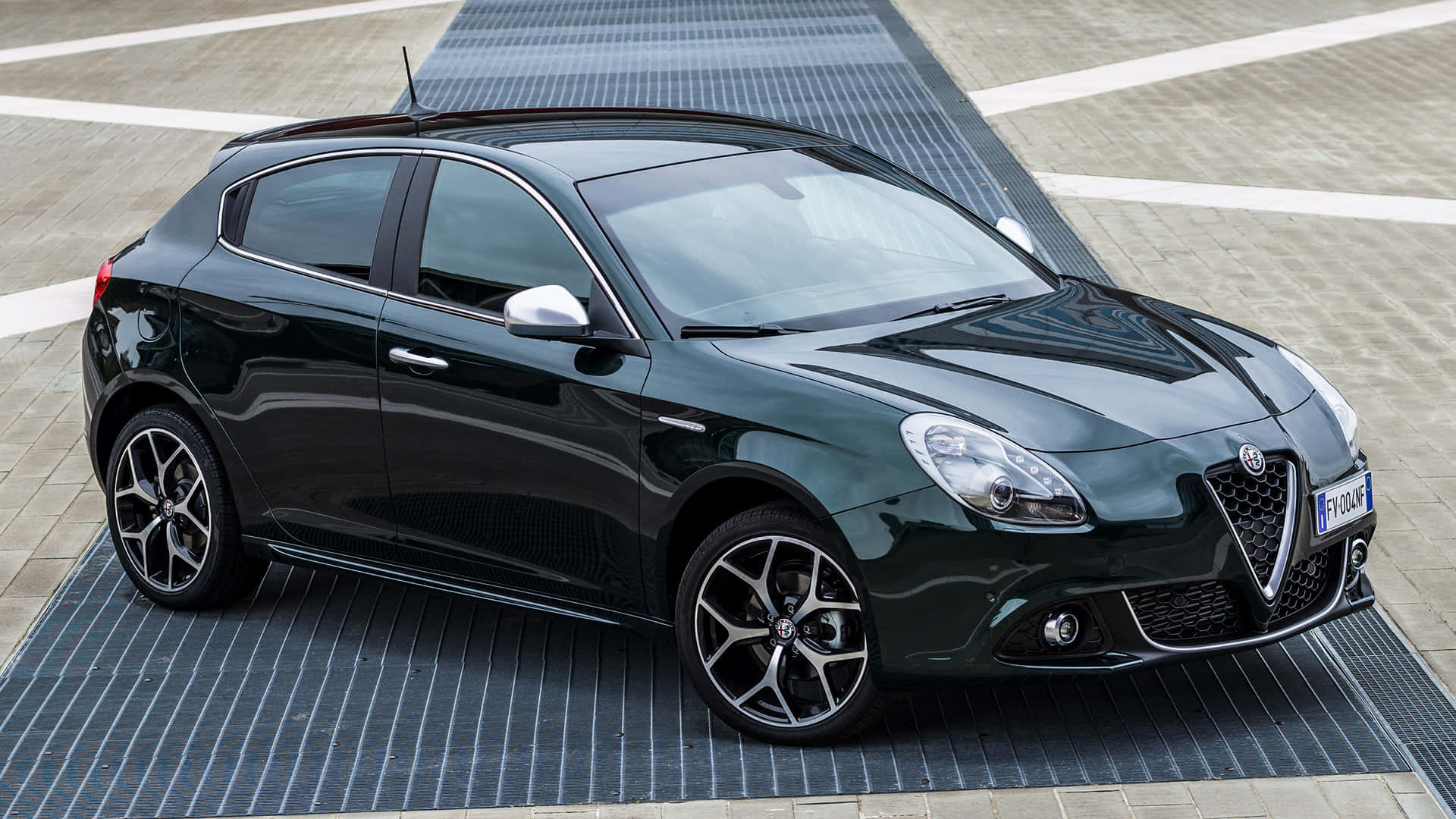 Alfa Romeo Giulietta 桌布 壁紙 — 一輛時尚的黑色愛快羅密歐Giulietta在明亮的日光下停放在條紋路面上。