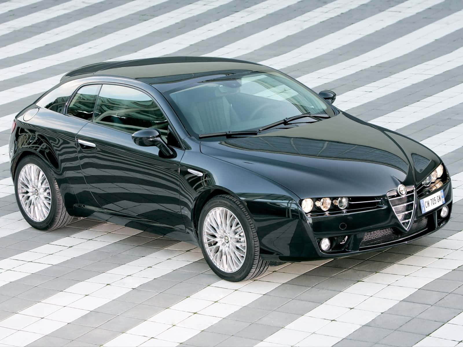 Alfa Romeo Brera 桌布 壁紙 — 一輛時尚的黑色愛快羅密歐運動轎跑車在灰白瓷磚斑馬線上閃耀，沐浴在明亮的日光下。