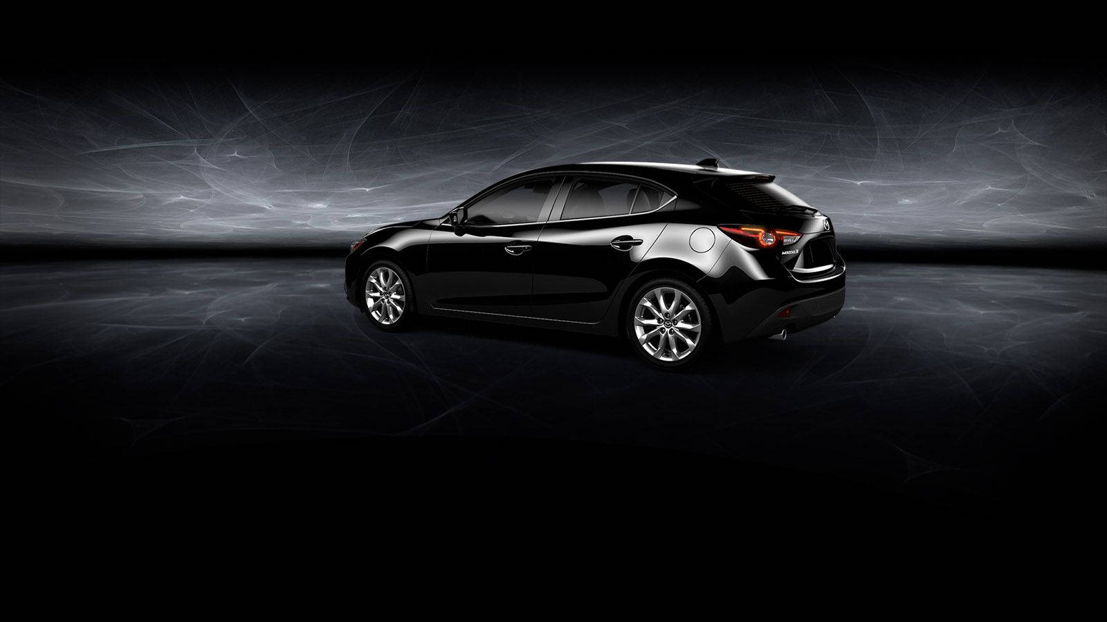Mazda 桌布 壁紙 — 一輛時尚的黑色掀背車在戲劇性的攝影棚燈光下，在黑暗的抽象背景中發光。