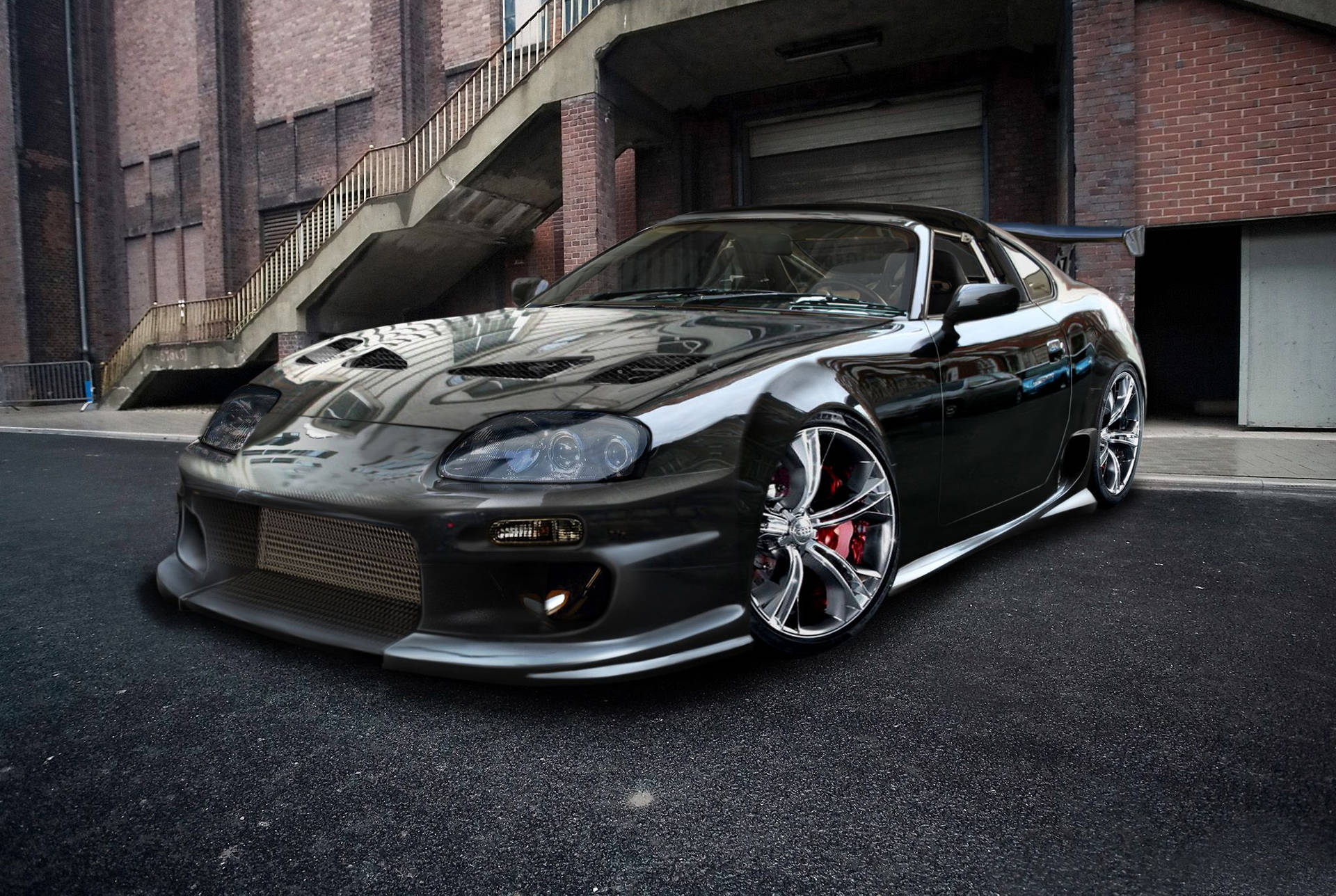 黑色改裝跑車帶紅色制動器停在磚砌建築附近的街道上。 — Toyota Supra Mk4 壁紙