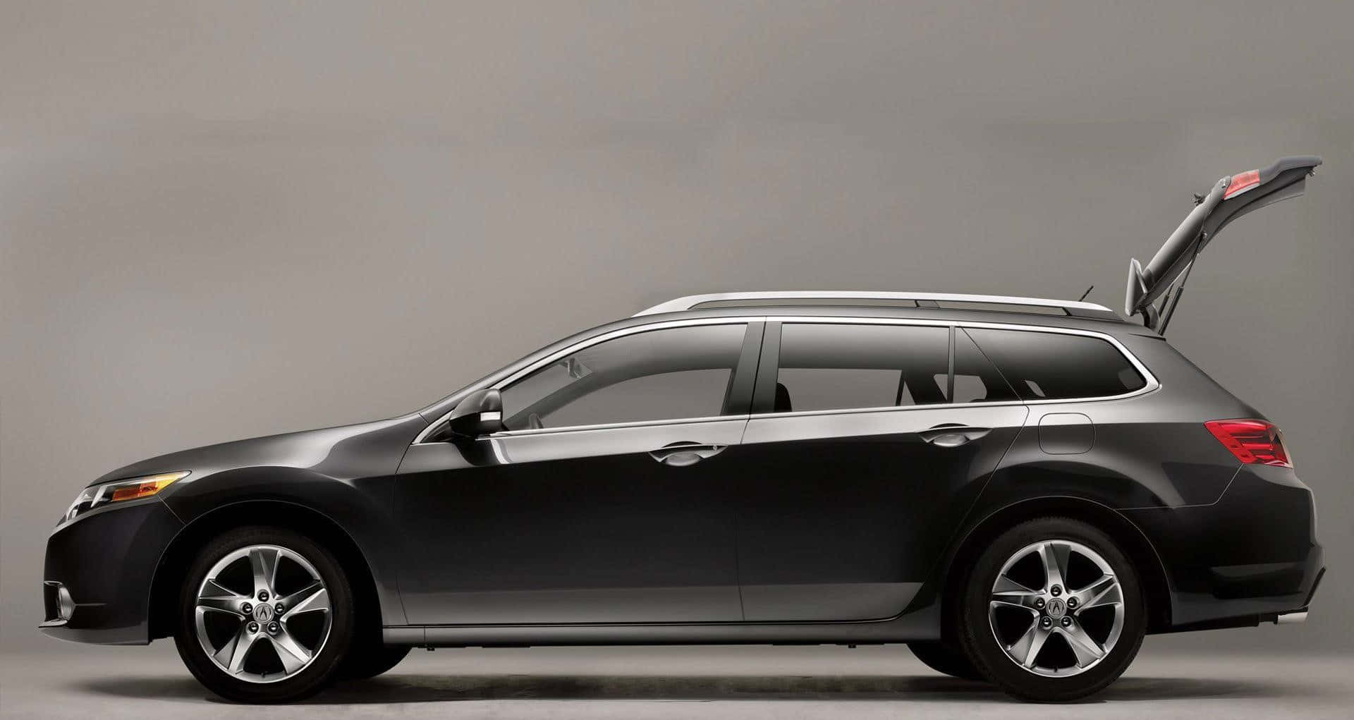 Acura Tsx 桌布 壁紙 — 一輛時尚的黑色旅行車，尾門打開，在簡約的工作室中，背景為中性灰色。