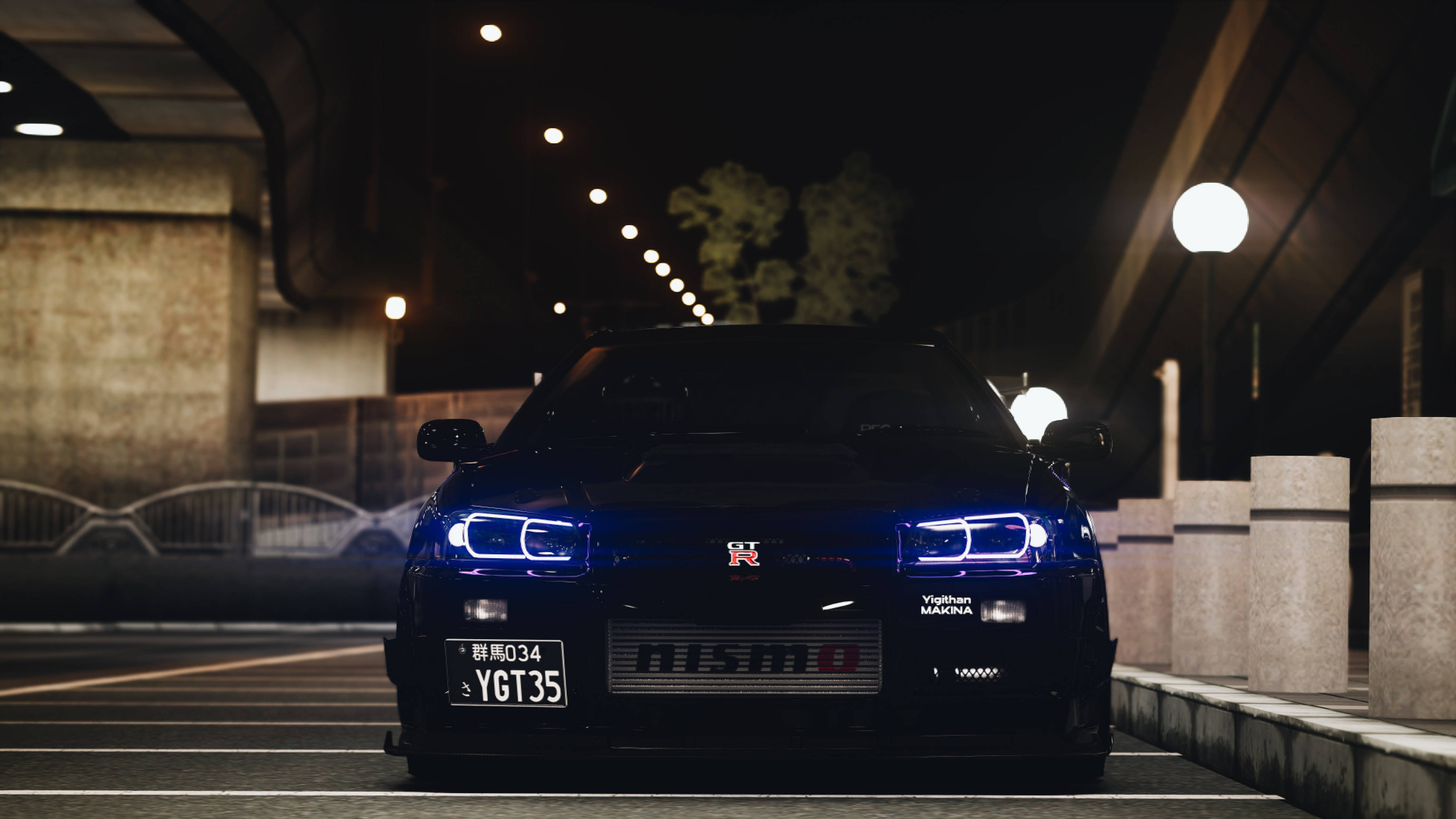 日產 桌布 壁紙 — 一輛時尚的黑色日產GT-R，帶有發光的藍色車頭燈，夜晚停放在昏暗的城市天橋下。
